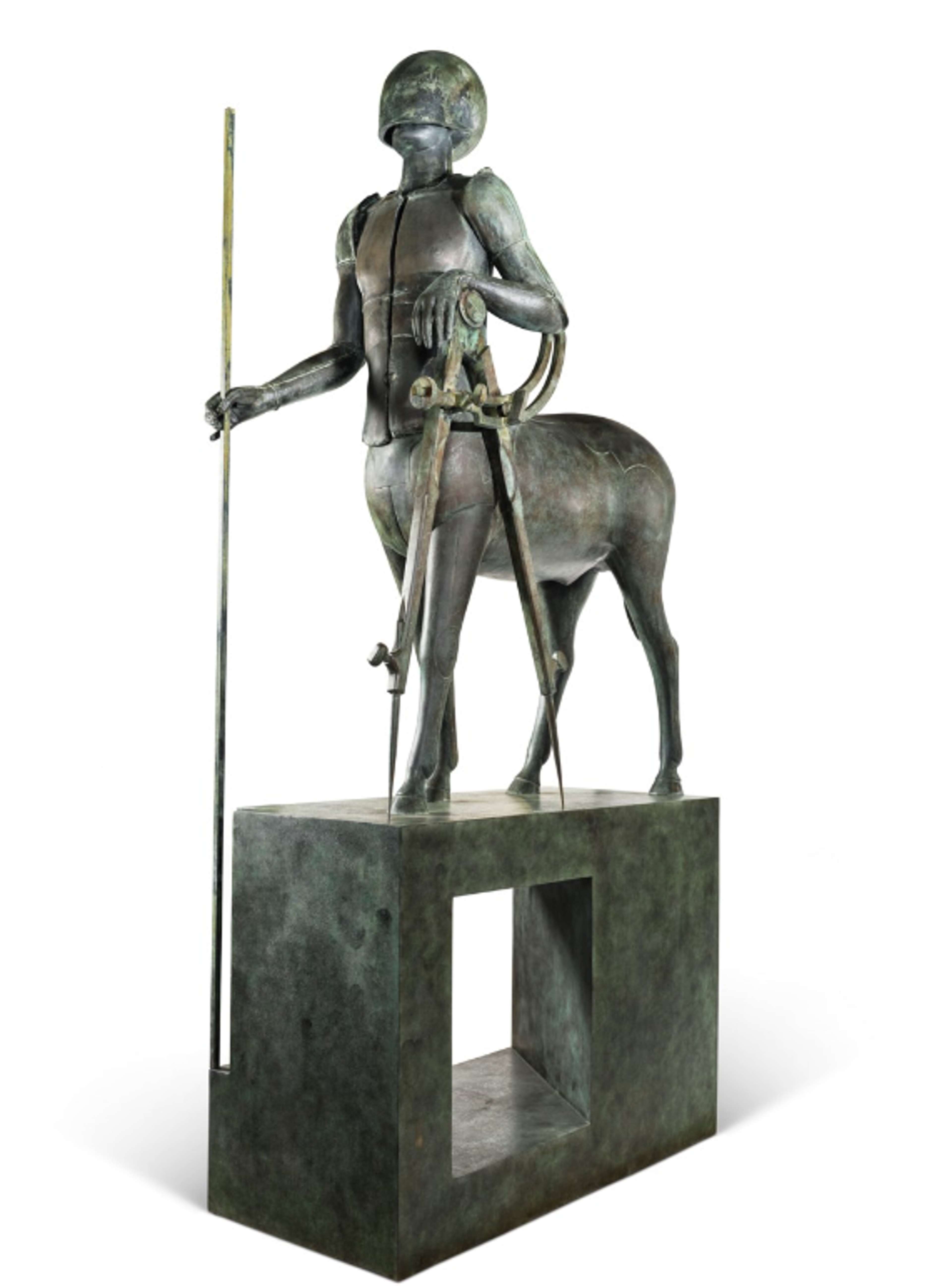 A bronze sculpture of a centaur (half-human, half-horse mythological figure) standing on top of a rectangular pedestal. He wears a helmet as well as armor on his torso, and leans against an upright compass. He holds a tall staff that reaches the ground below the pedestal and has a dignified, powerful stance. 