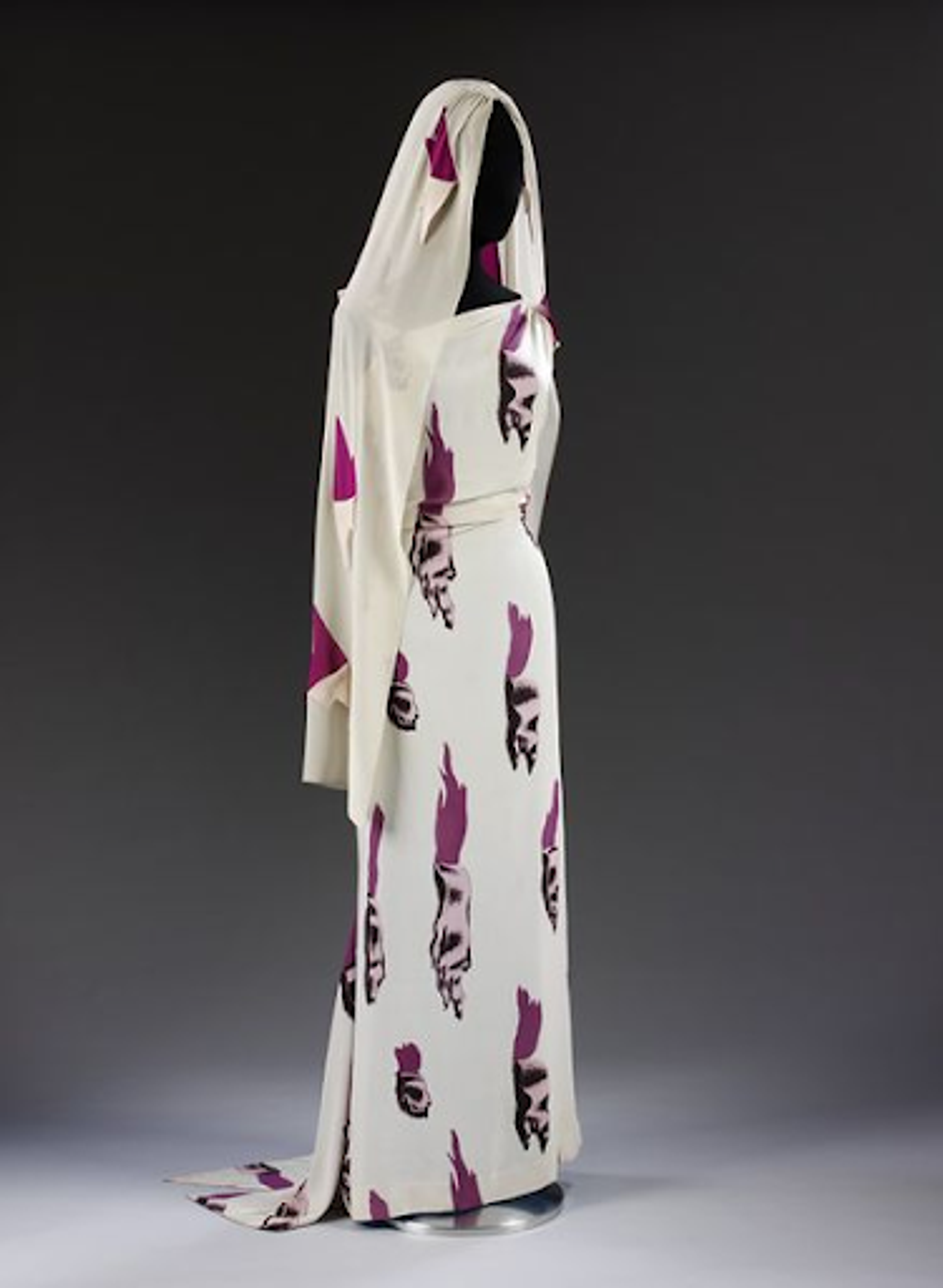Photographie d'une longue robe blanche et d'un voile assorti, ornés de motifs violets.