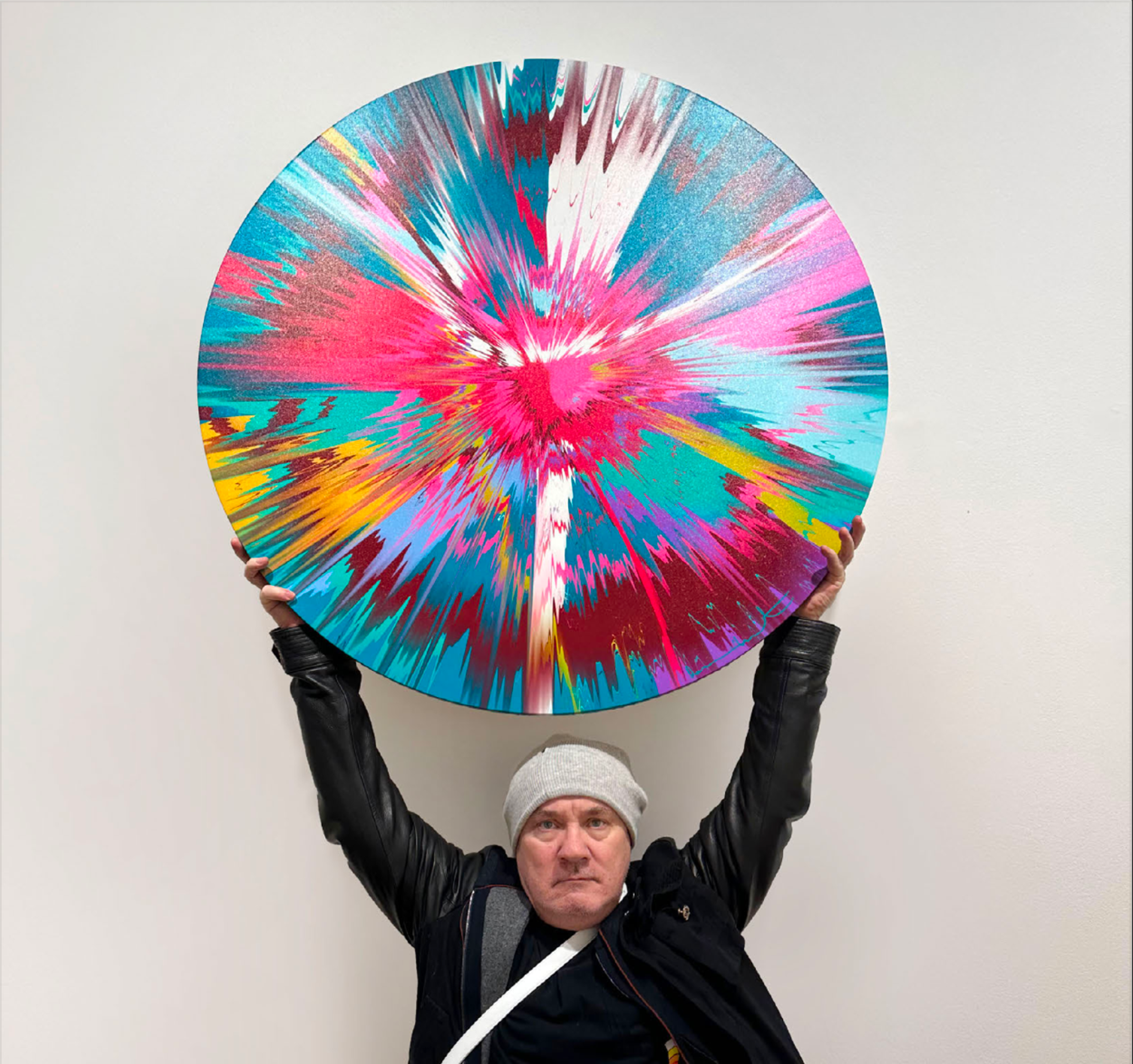 Damien Hirst tenant une œuvre circulaire multicolore