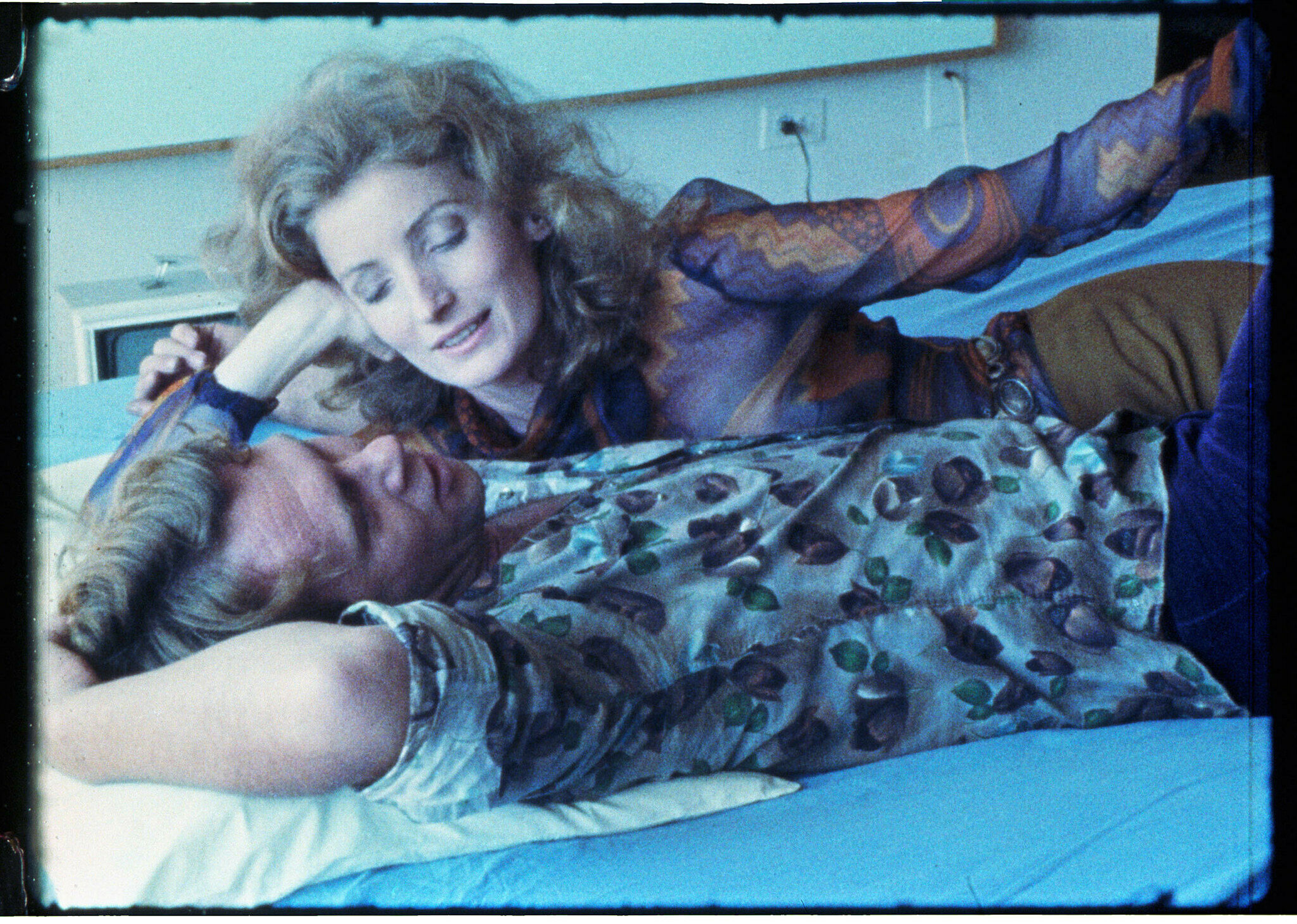 Une image tirée du film « Blue Movie » d'Andy Warhol. Elle montre un couple allongé sur un lit, la femme regardant le visage de l'homme.