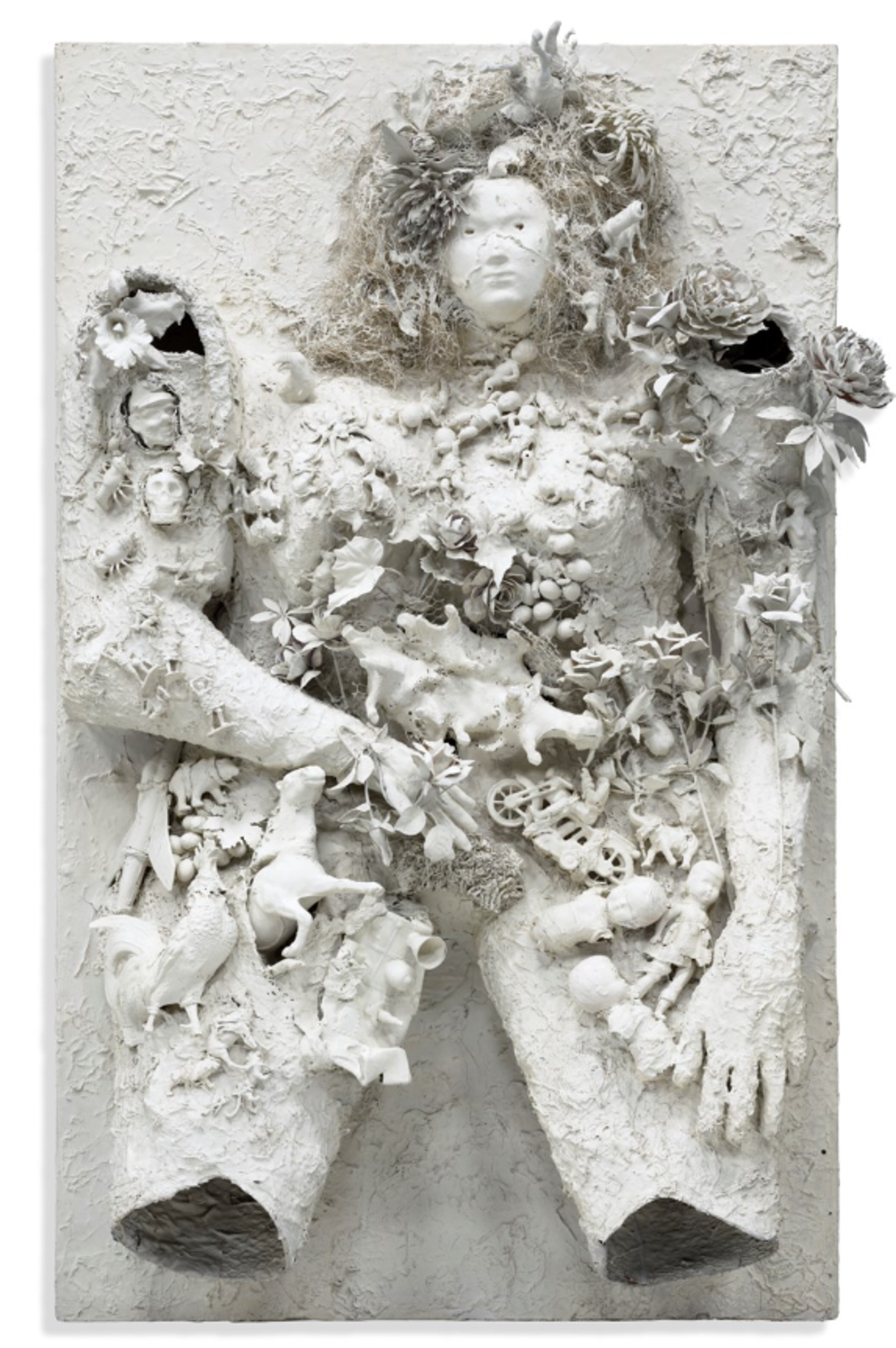 A white plaster relief sculpture depicting a female figure embedded with flowers, leaves, shells, and other organic forms. The figure appears to emerge from or sink into the textured background, creating an ethereal, dreamlike quality.
