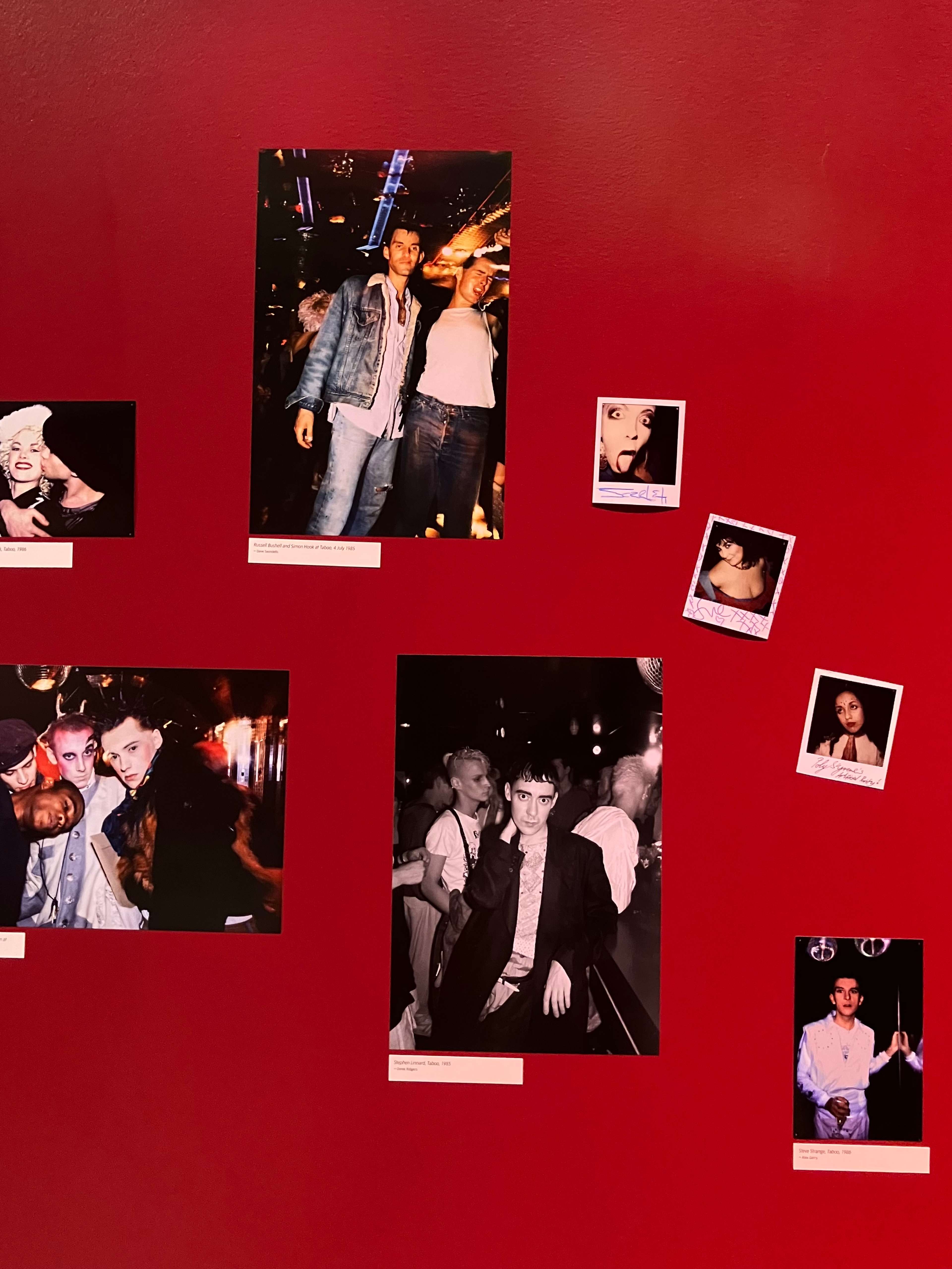 Des photographies avec des légendes accrochées à un mur rouge
