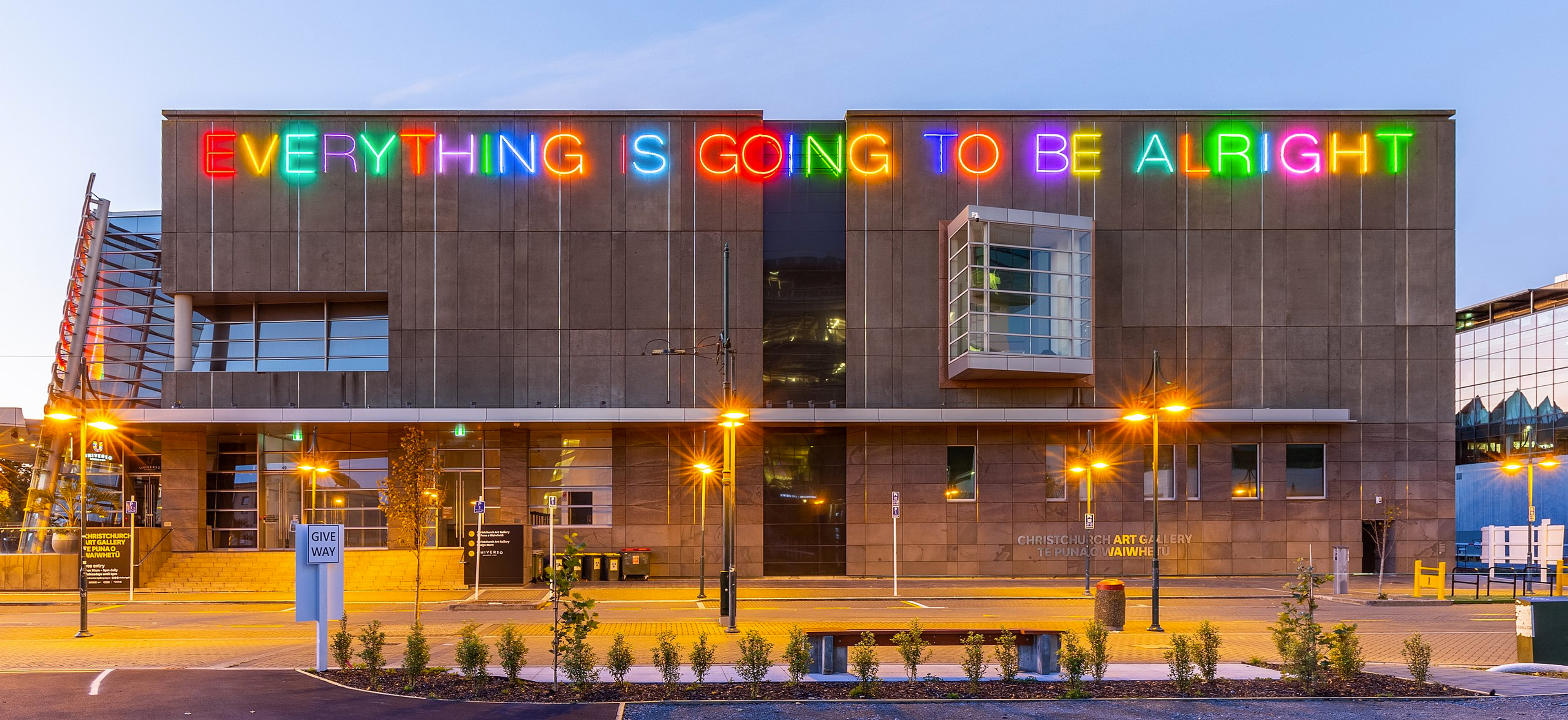 La façade de la Christchurch Art Gallery en Nouvelle-Zélande, ornée de lettres au néon colorées indiquant « Everything is going to be alright »