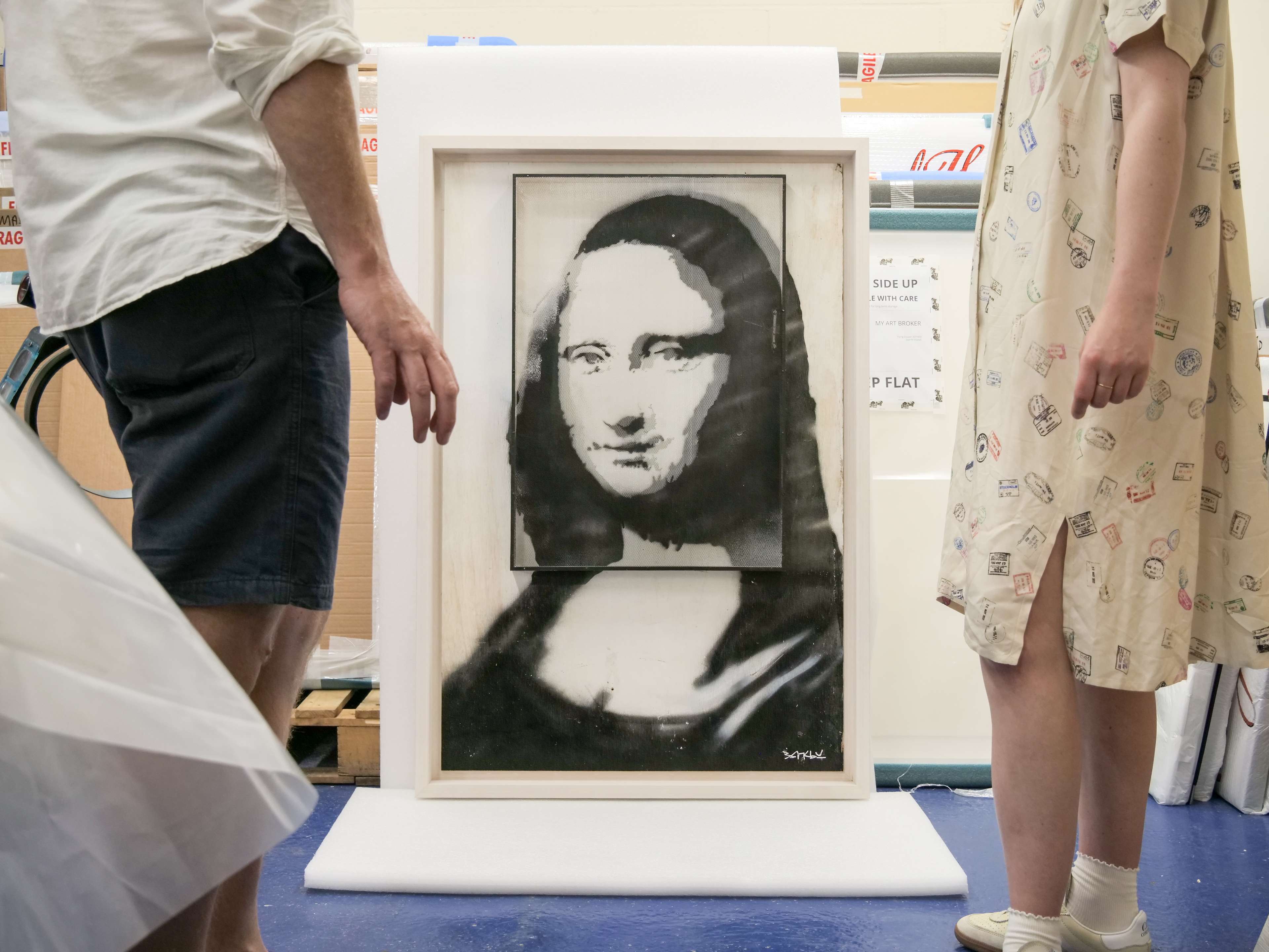 La Joconde sur résille de Banksy, flanquée de deux figures debout.