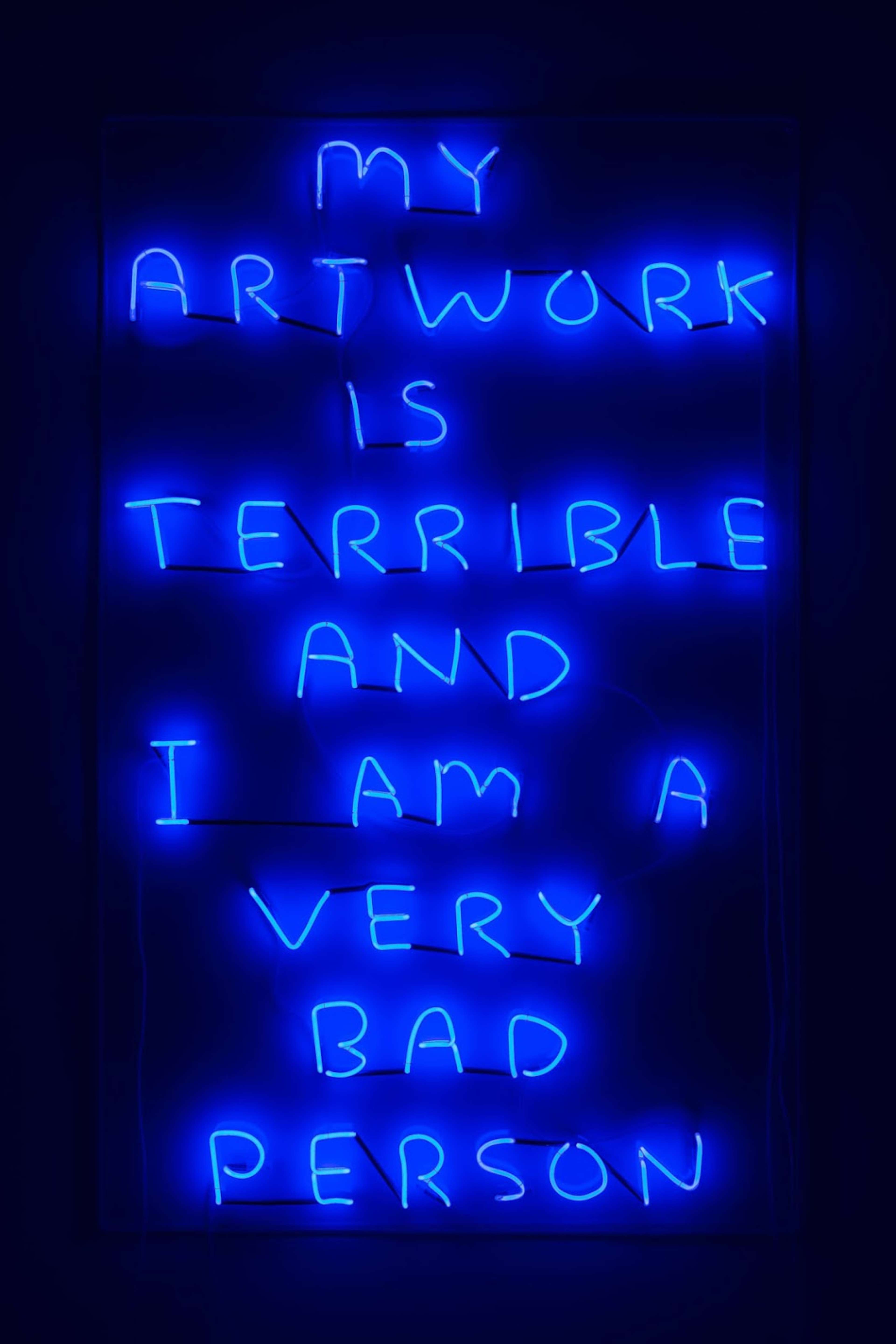 Une image de l'enseigne au néon « My Artwork Is Terrible » de l'artiste David Shrigley, un néon bleu qui affiche : « My artwork is terrible and I am a very bad person. »