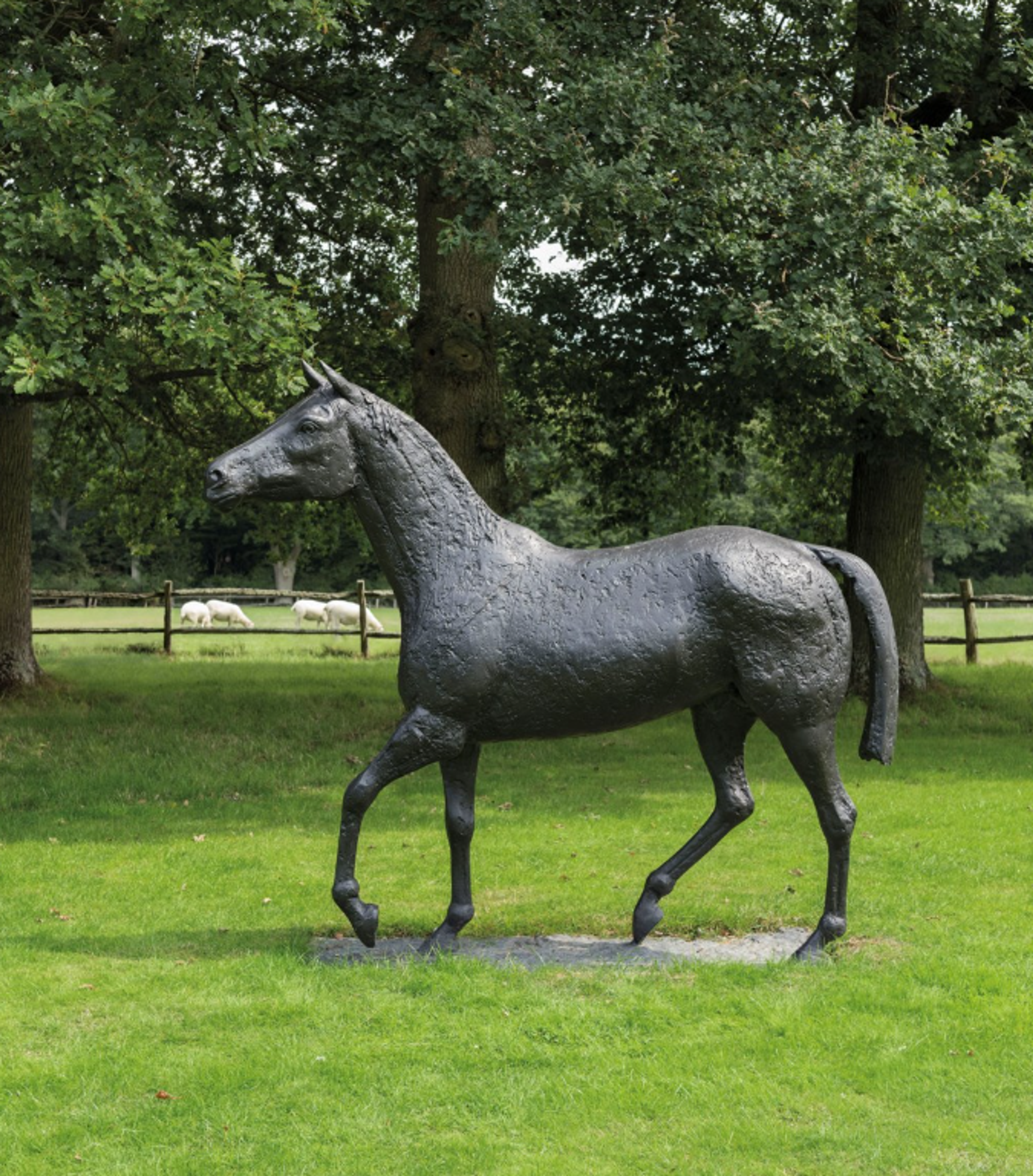 A bronze sculpture of a horse walking or trotting. Its front left and back right legs are bent as if in motion. Despite its scale and the textured finish of the bronze, the suggestion of movement makes it appear light.