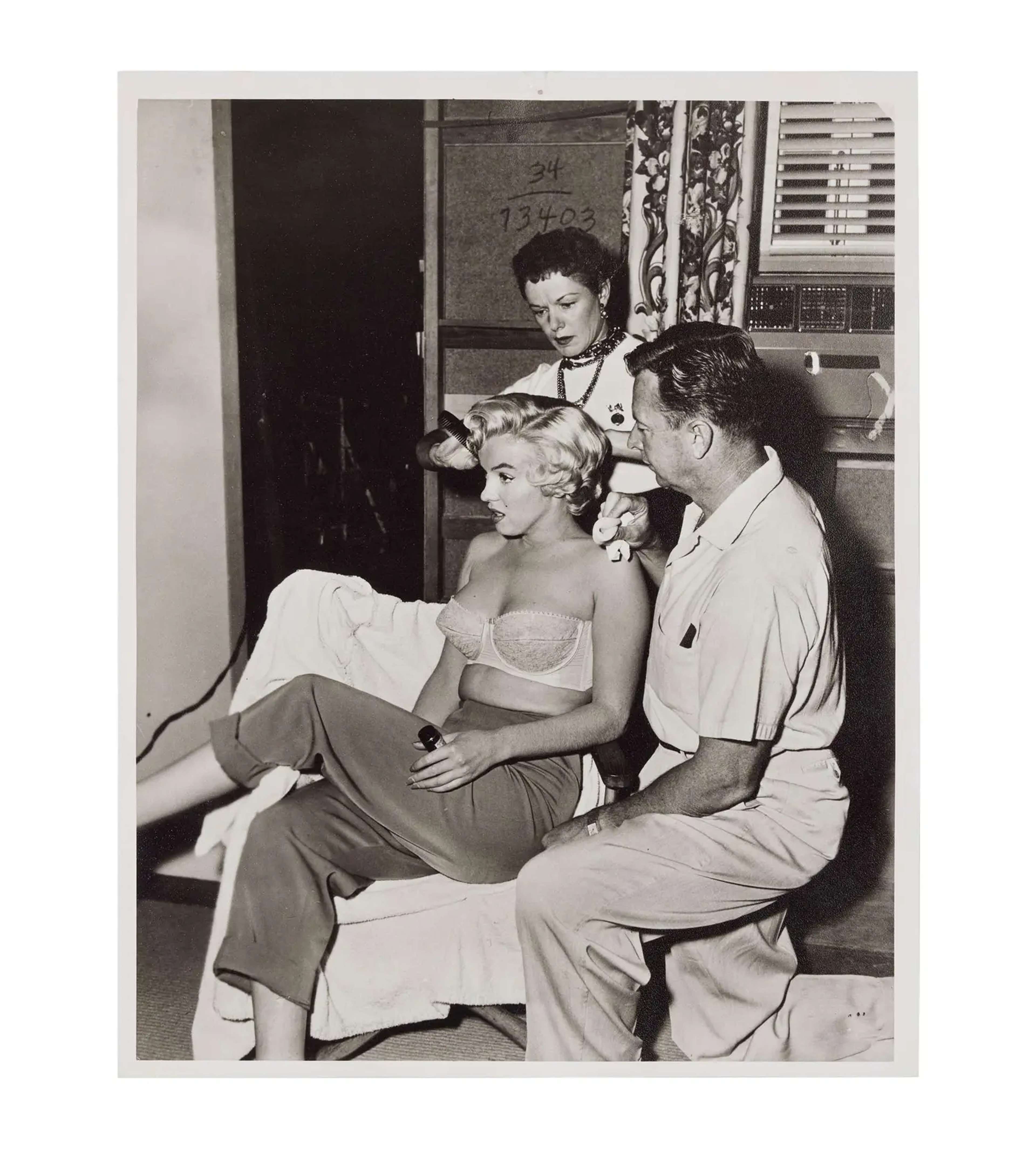 Black-and-white 1954 photograph of Marilyn Monroe with her make-up team in an informal group portrait.