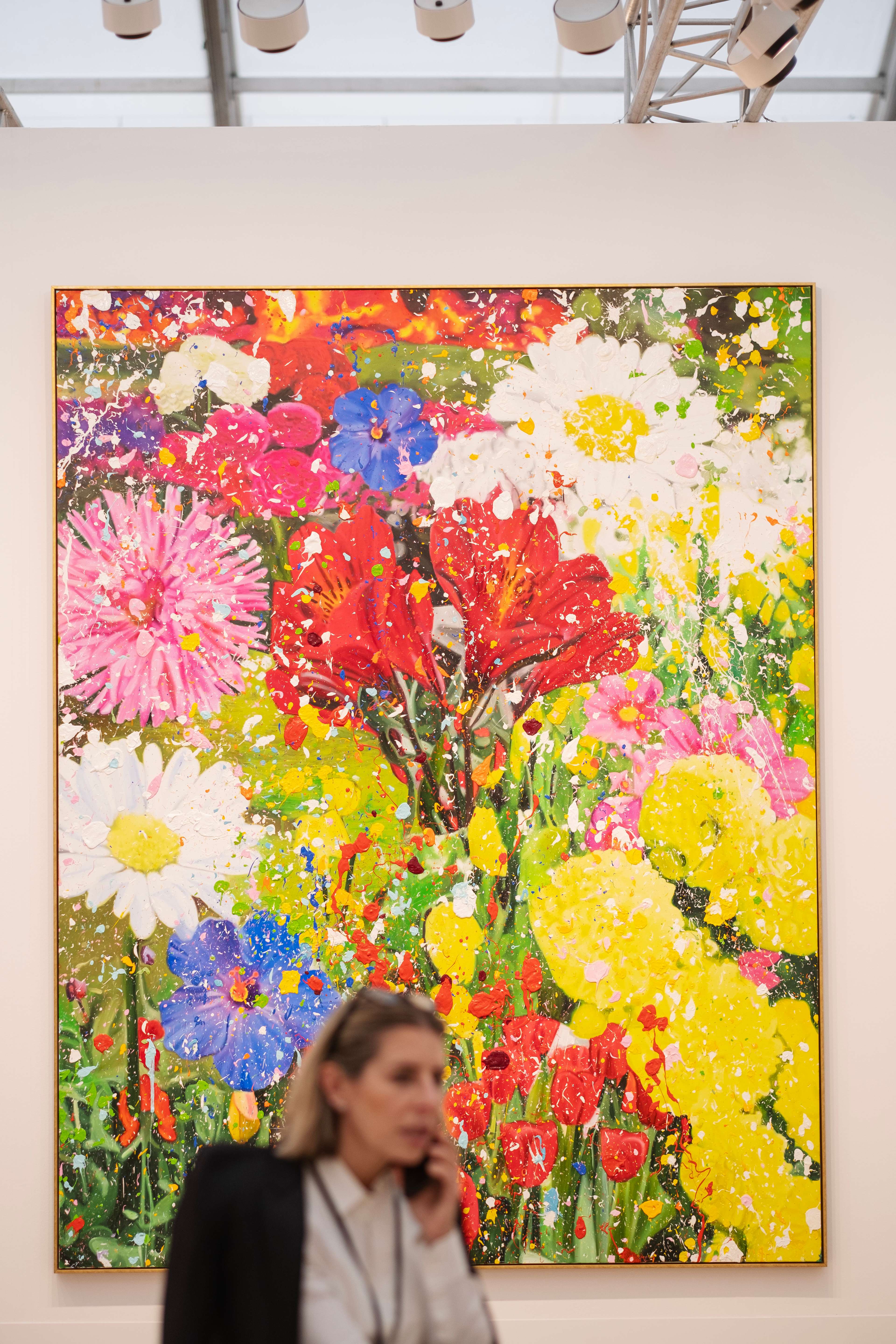 Image d'une femme devant une grande peinture de Damien Hirst présentée au stand Gagosian lors de Frieze London 2023.