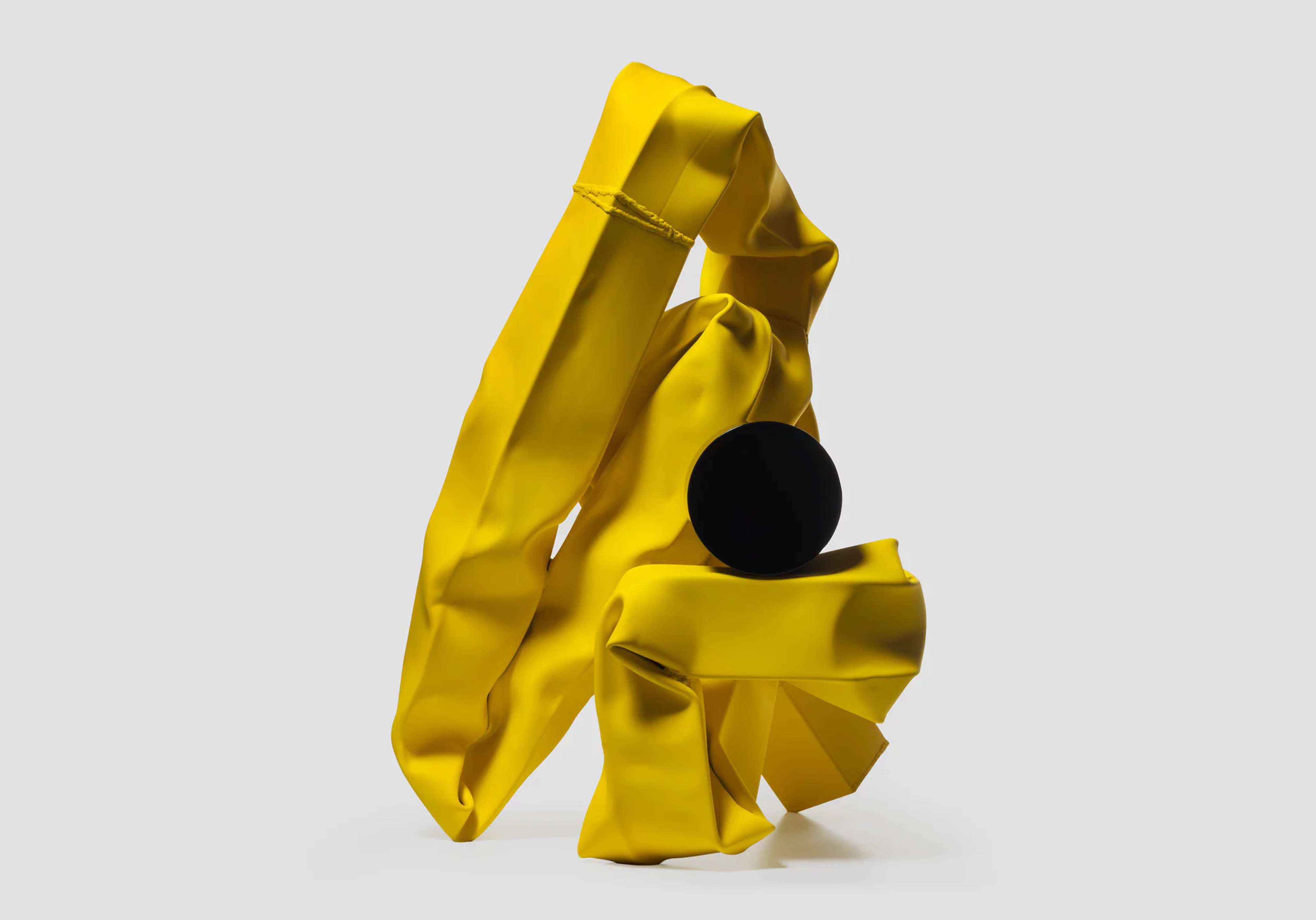 Sculpture jaune torsadée avec une boule noire au centre