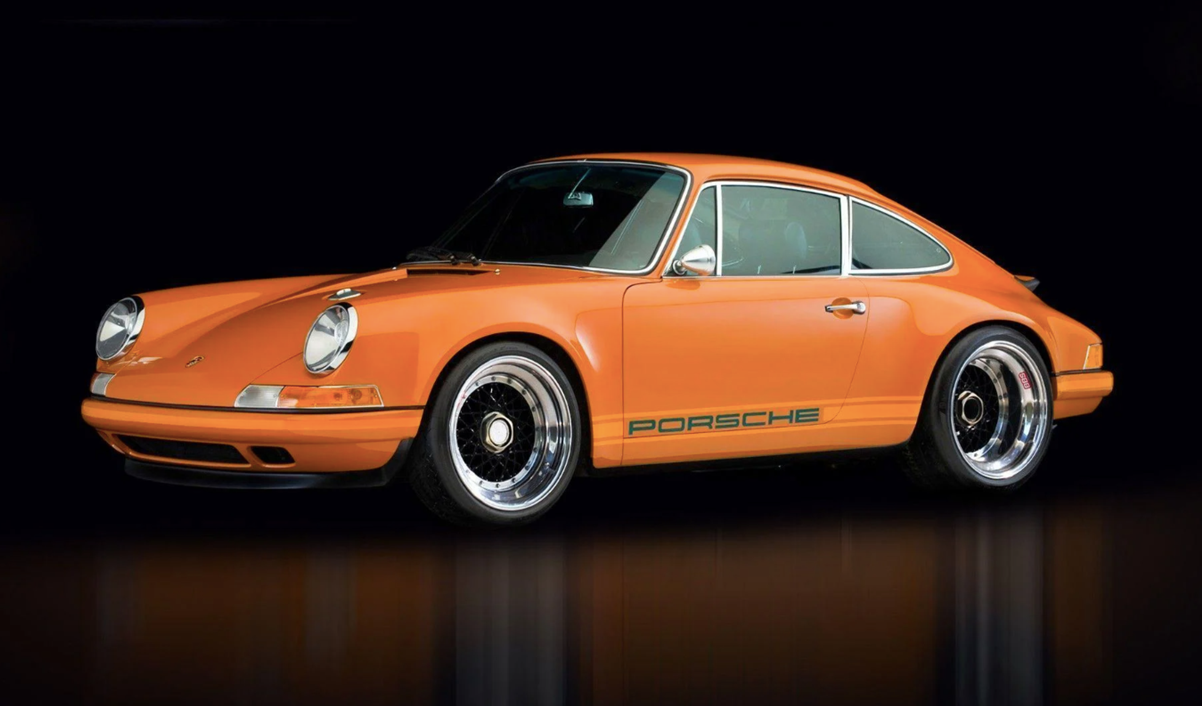 Une Porsche 911 de première génération de couleur orange sur fond sombre.