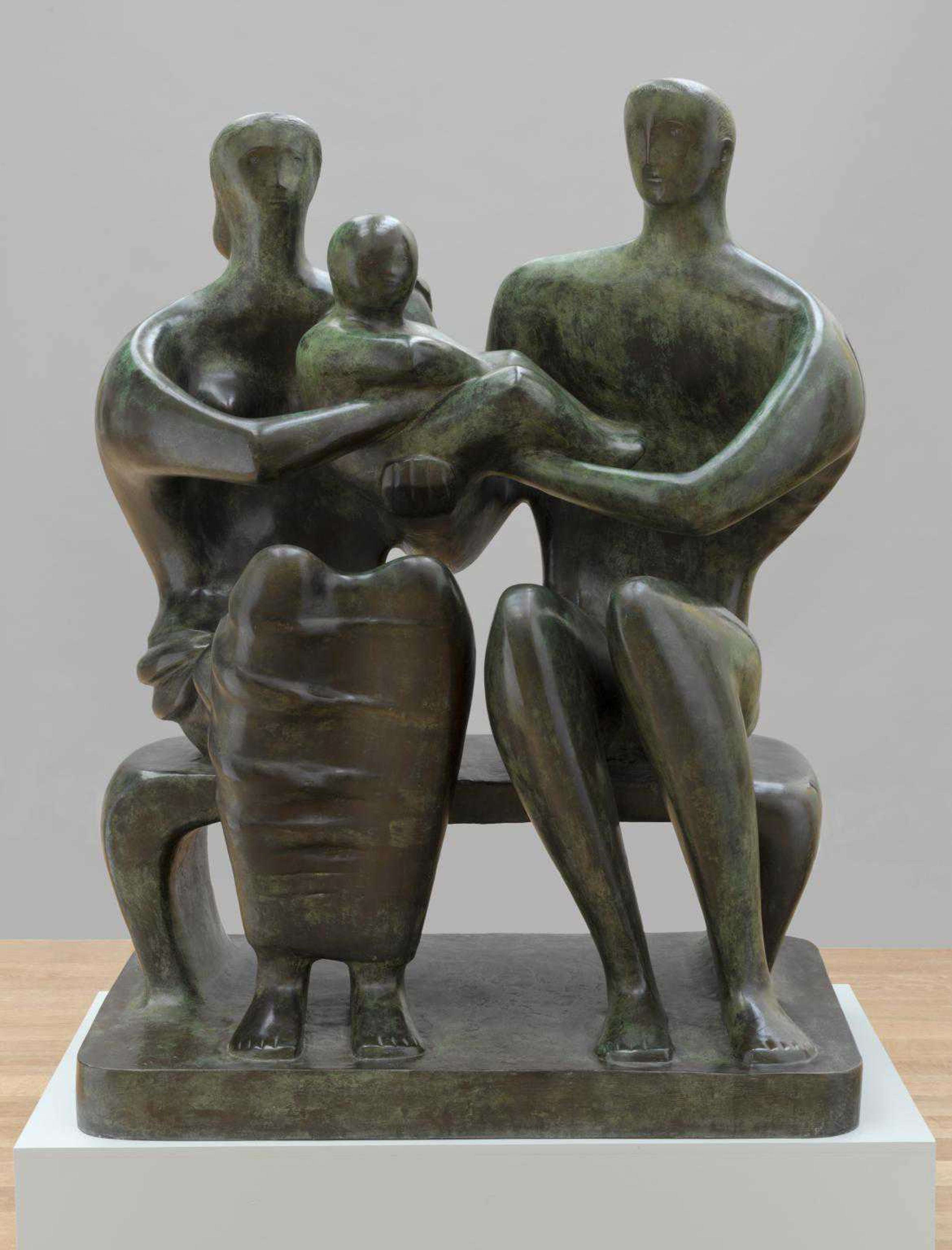 Sculpture représentant trois figures, deux assises et une tenue dans les bras, symbolisant un lien familial.