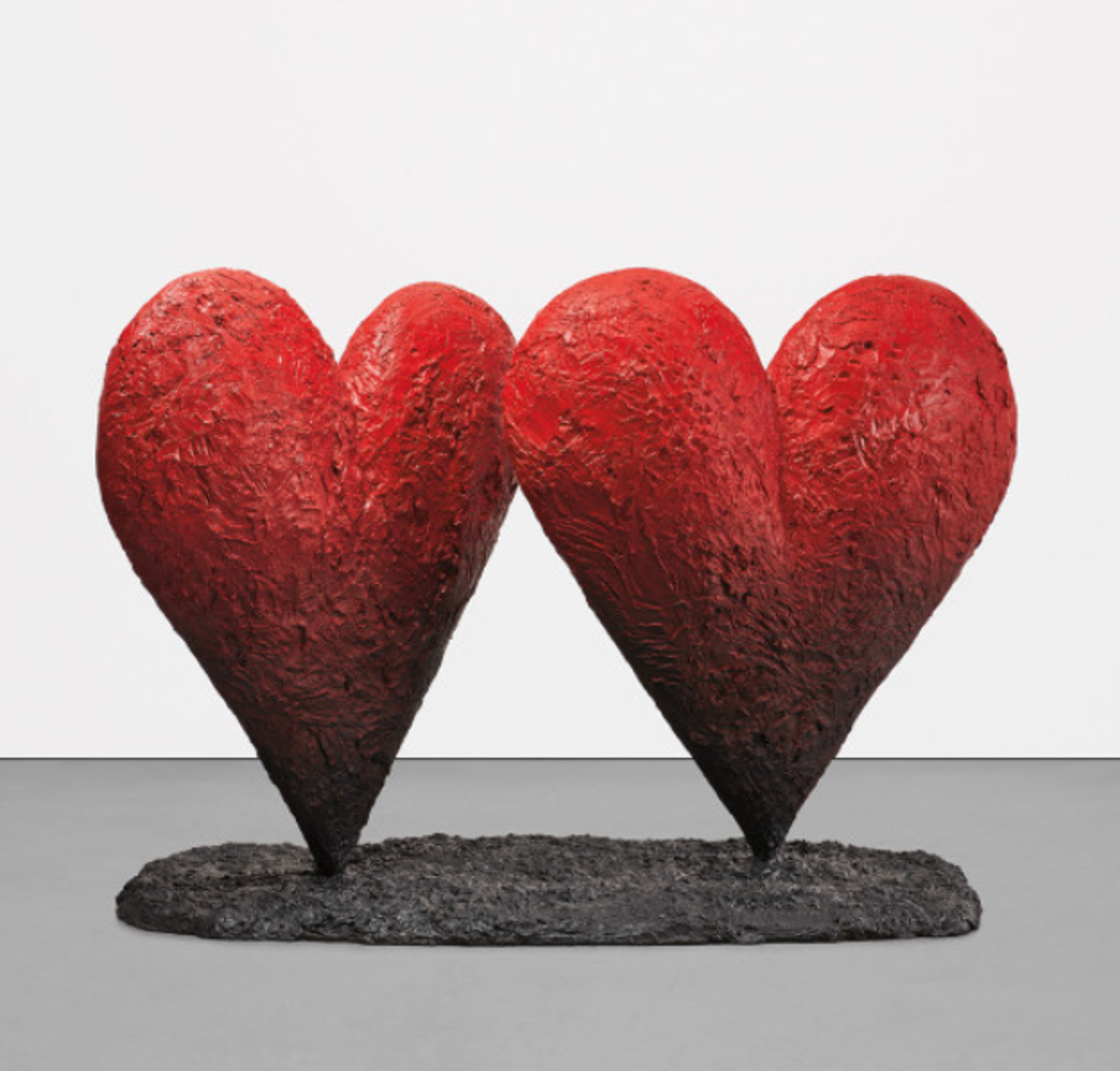 Two tall heart-shaped sculptures on a textured black base. One heart turns slightly towards the other. Both are red, which fades into black towards the base, with richly textured surfaces.