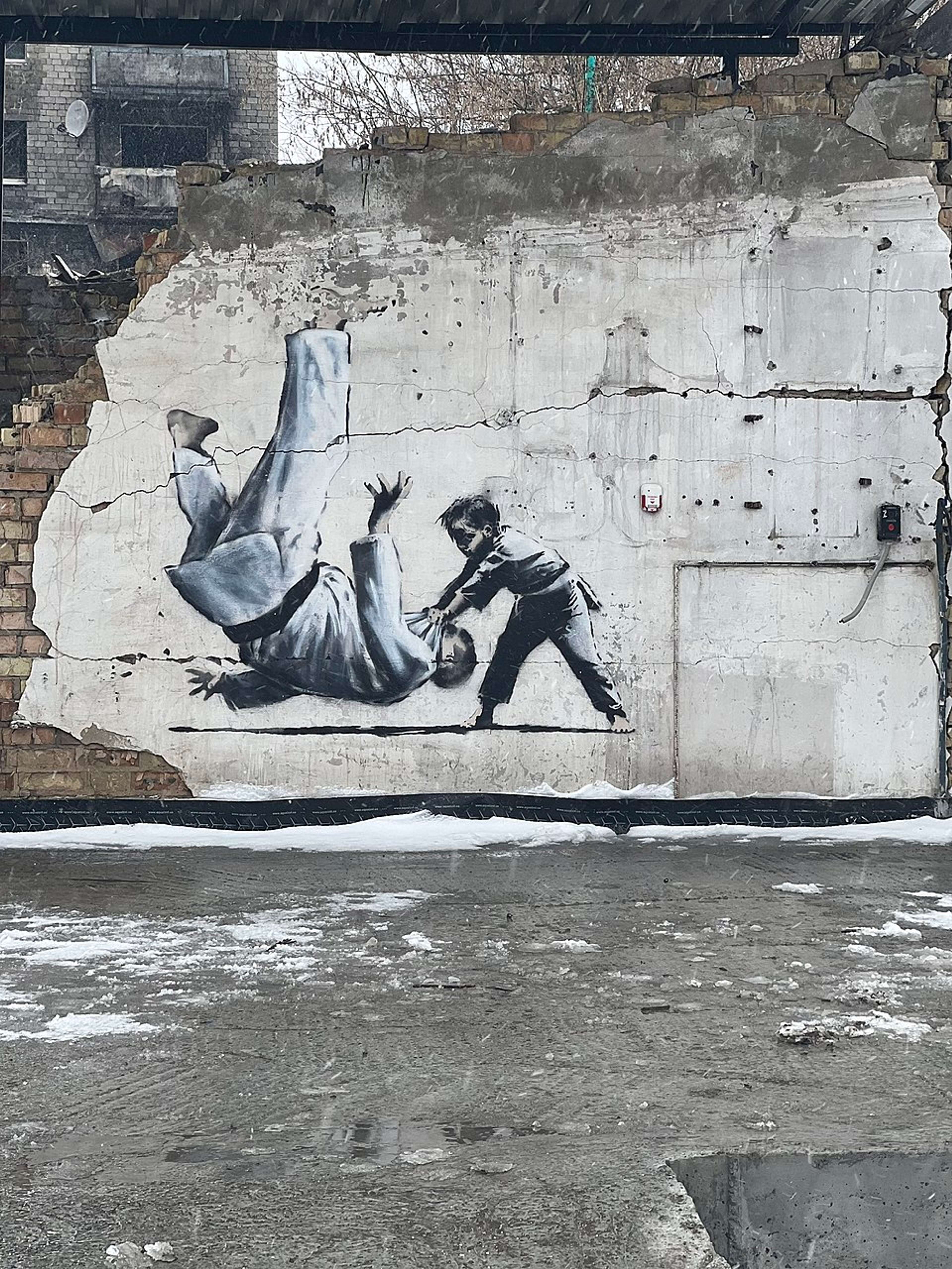 Fresque murale de Banksy dans la ville de Borodianka, en Ukraine, représentant un enfant faisant un mouvement de judo pour projeter un homme ressemblant à Poutine