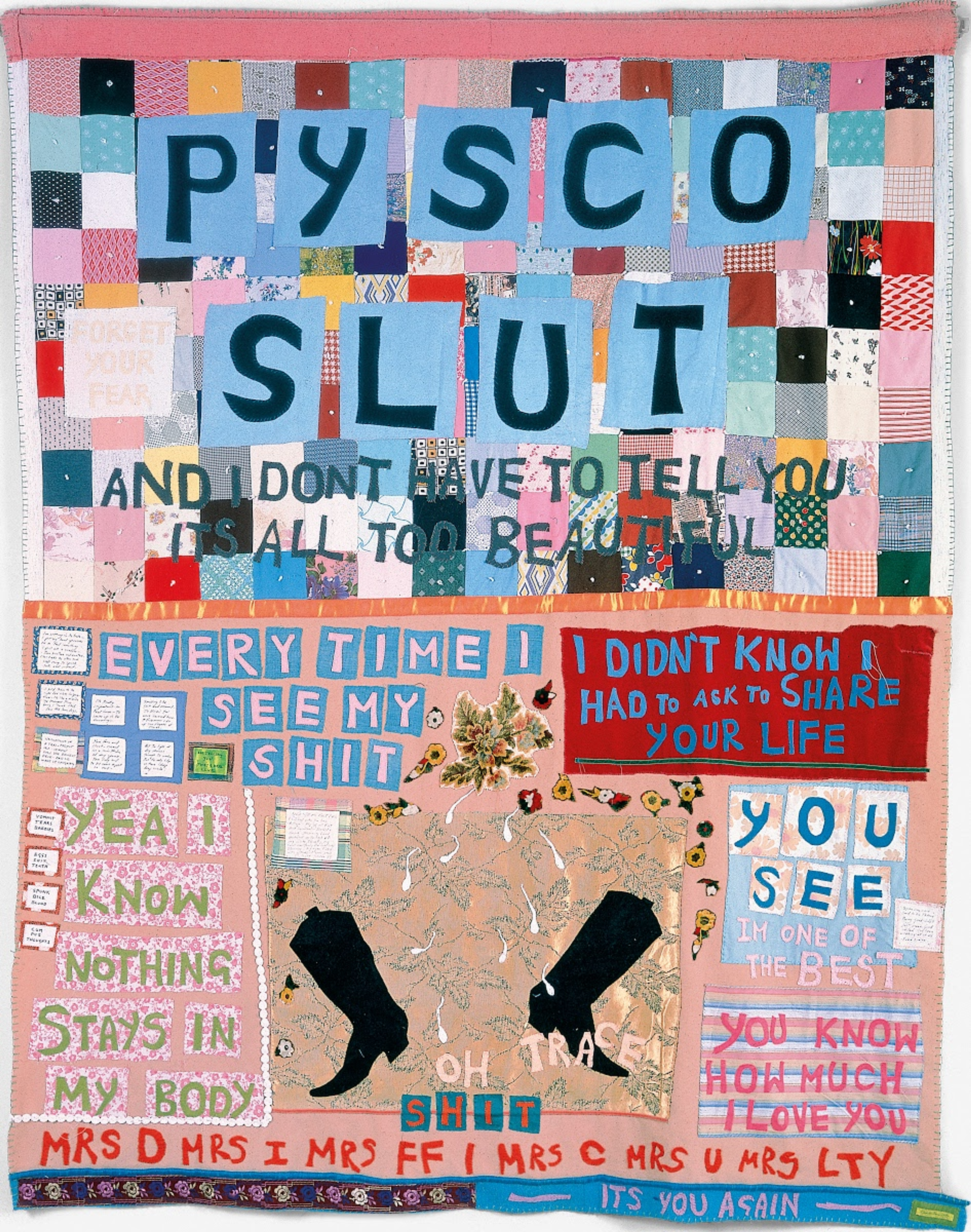 « Psycho Slut » de Tracey Emin. Une œuvre textile représentant une courtepointe aux tons roses et orangés, ornée de textes multicolores.