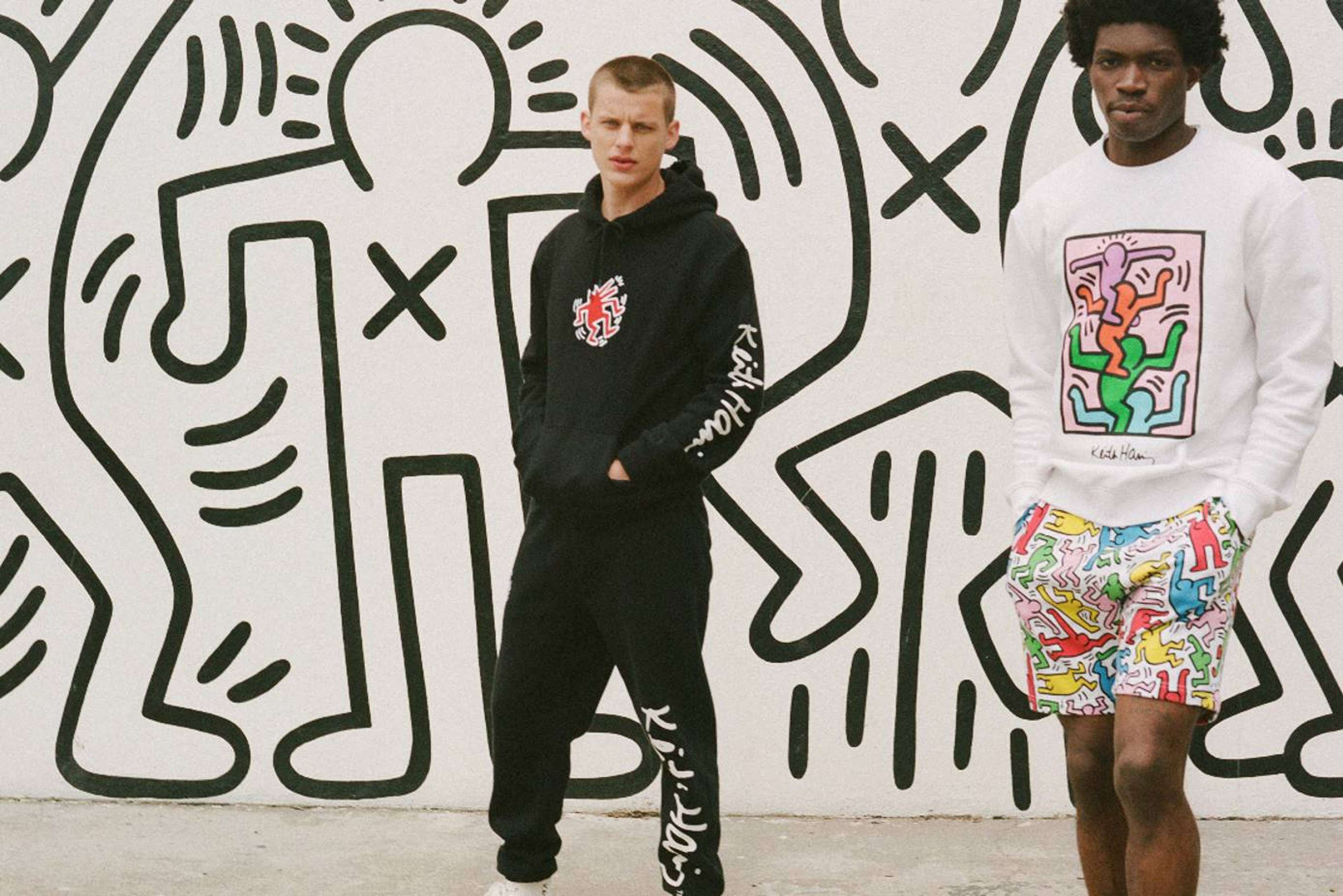 Une photo de deux mannequins portant des vêtements issus de la collaboration entre H&M et Keith Haring, posant devant un arrière-plan montrant l'une des fresques emblématiques de l'artiste.