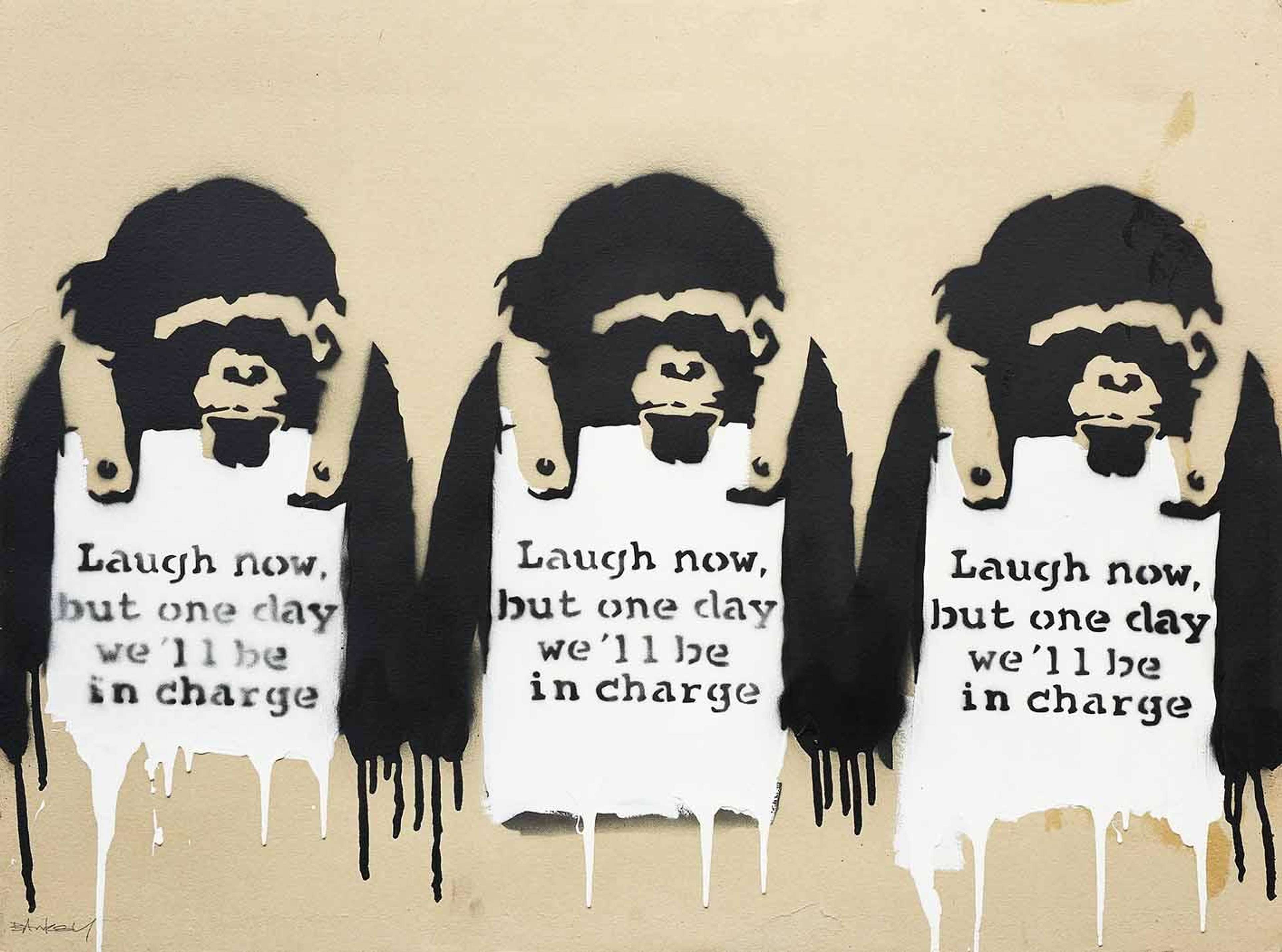 Trois singes de Banksy peints à la bombe aérosol, portant des pancartes indiquant « Laugh Now, But One Day We’ll Be In Charge »