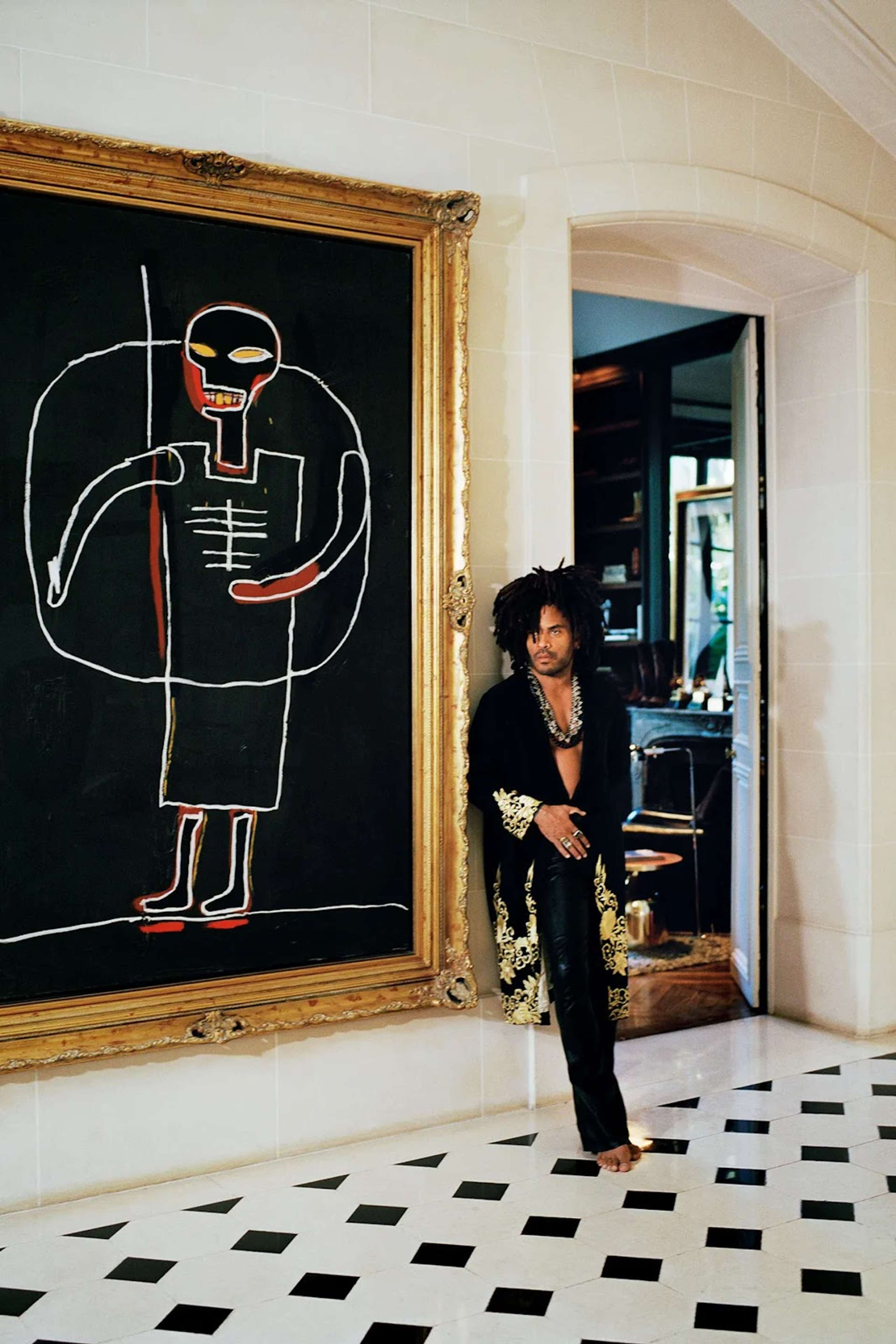 Photographie de Lenny Kravitz posant à côté d'une peinture de Jean-Michel Basquiat dans sa demeure. Photographie de Lenny Kravitz posant à côté d'une peinture de Jean-Michel Basquiat dans sa demeure, intitulée « At Home ».