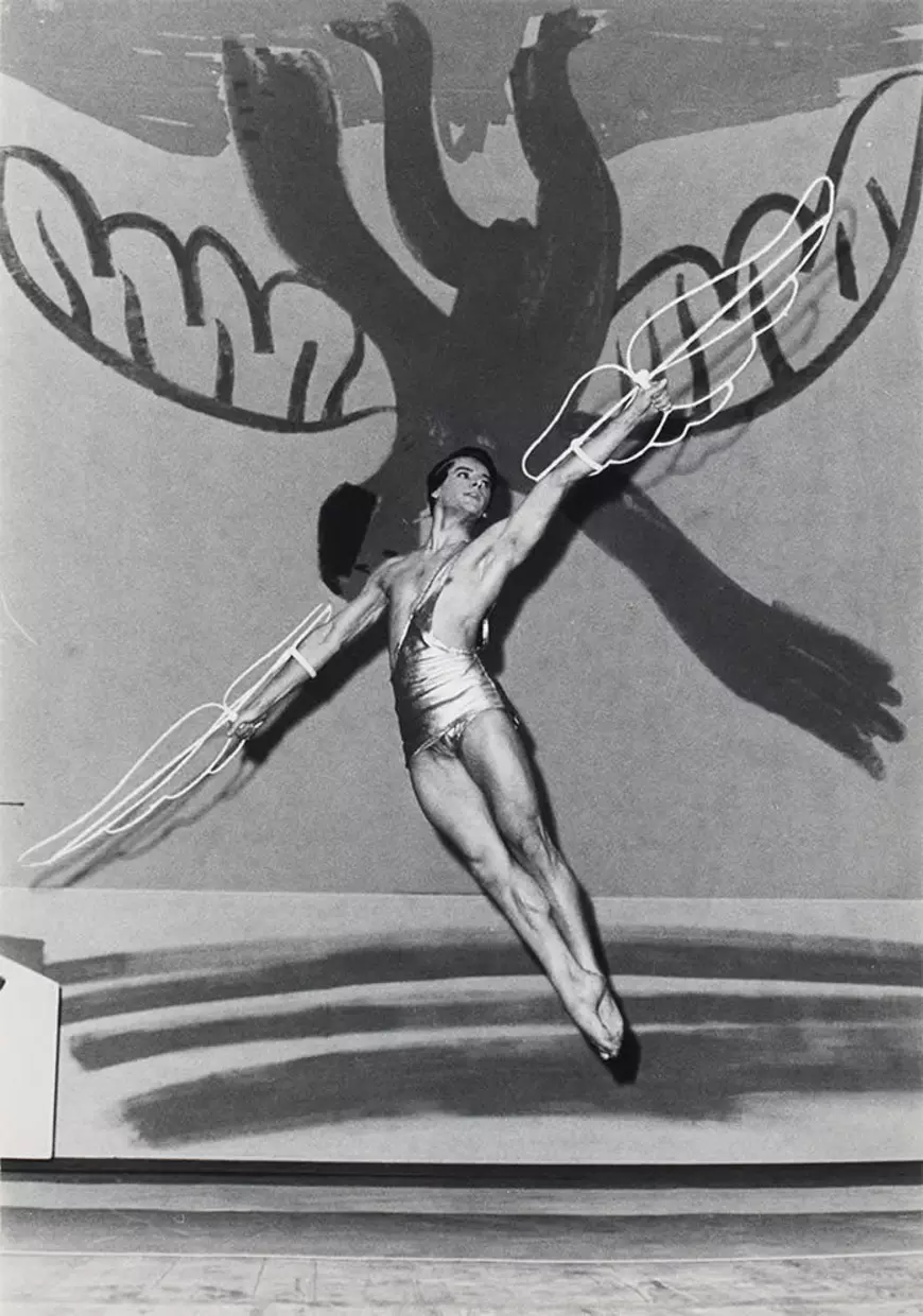 Une image monochrome d'une danseuse, portant des ailes en fil de fer, sur fond de la Chute d'Icare peinte par Pablo Picasso.