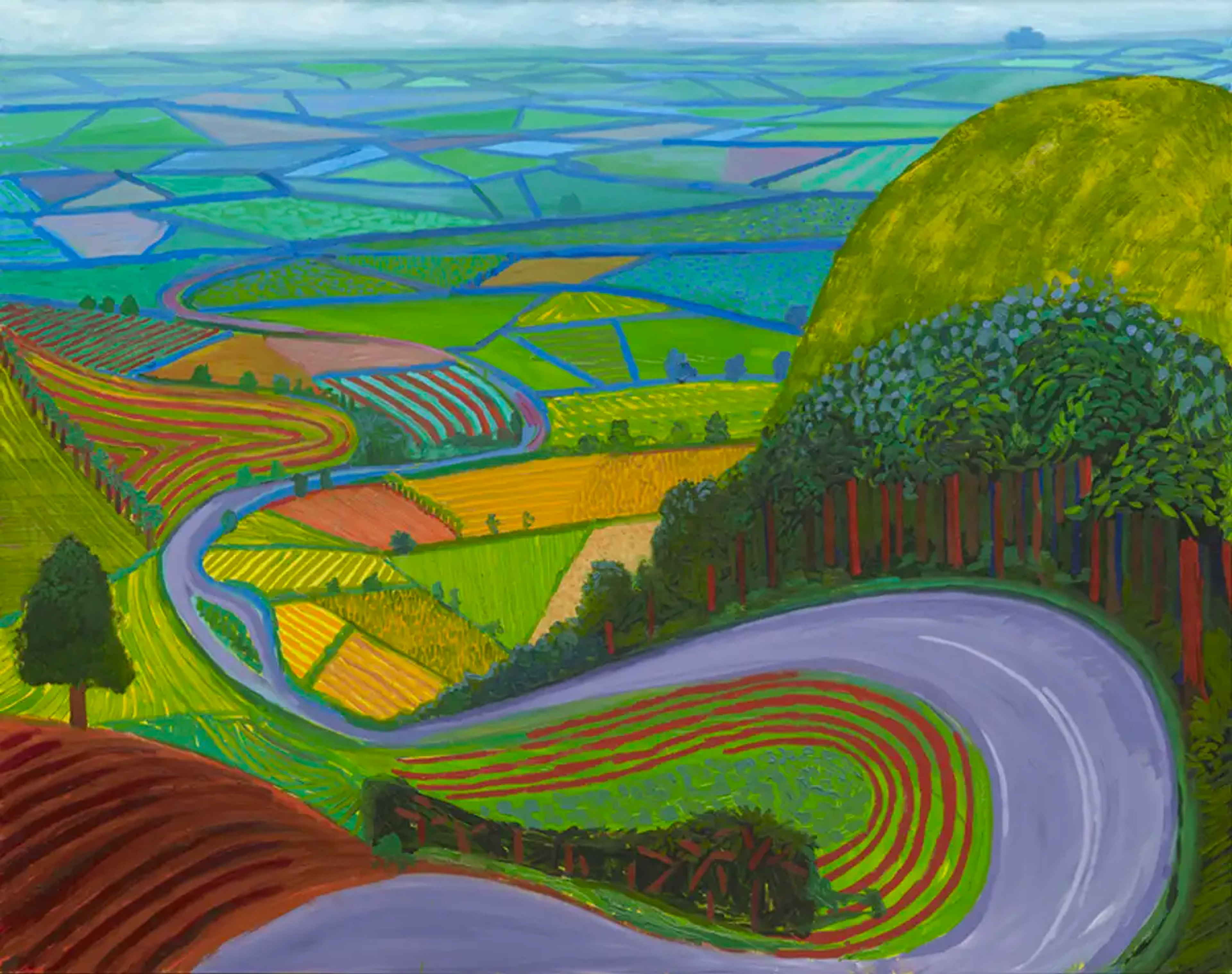Une route sinueuse en descente dans la campagne anglaise, vue depuis le sommet de la colline.