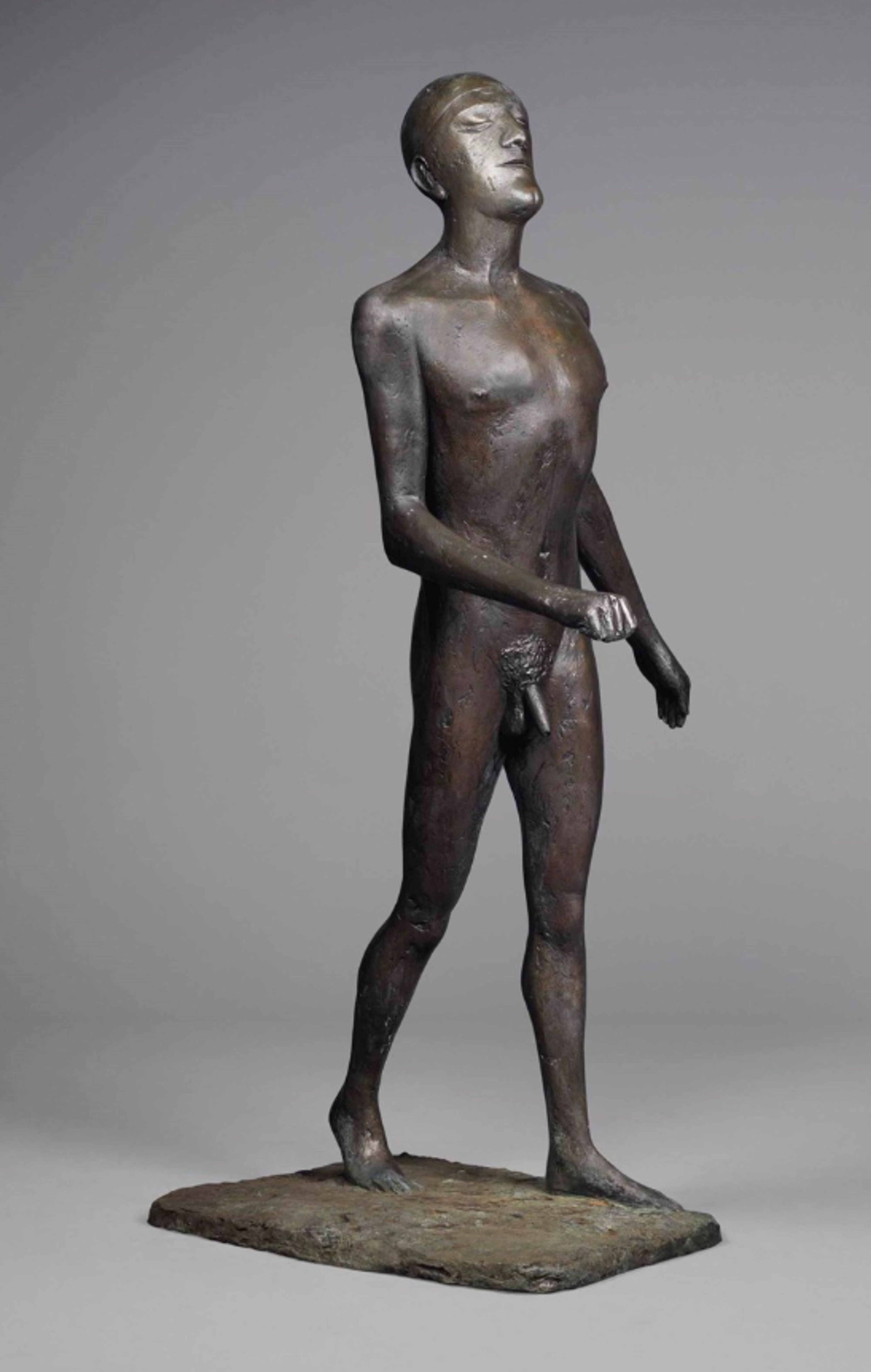 A textured bronze sculpture of a naked male figure. He is mid-stride, with his left foot forward. Both arms are swinging forward, with the right raised to waist-height. He is turning his face towards the sky.