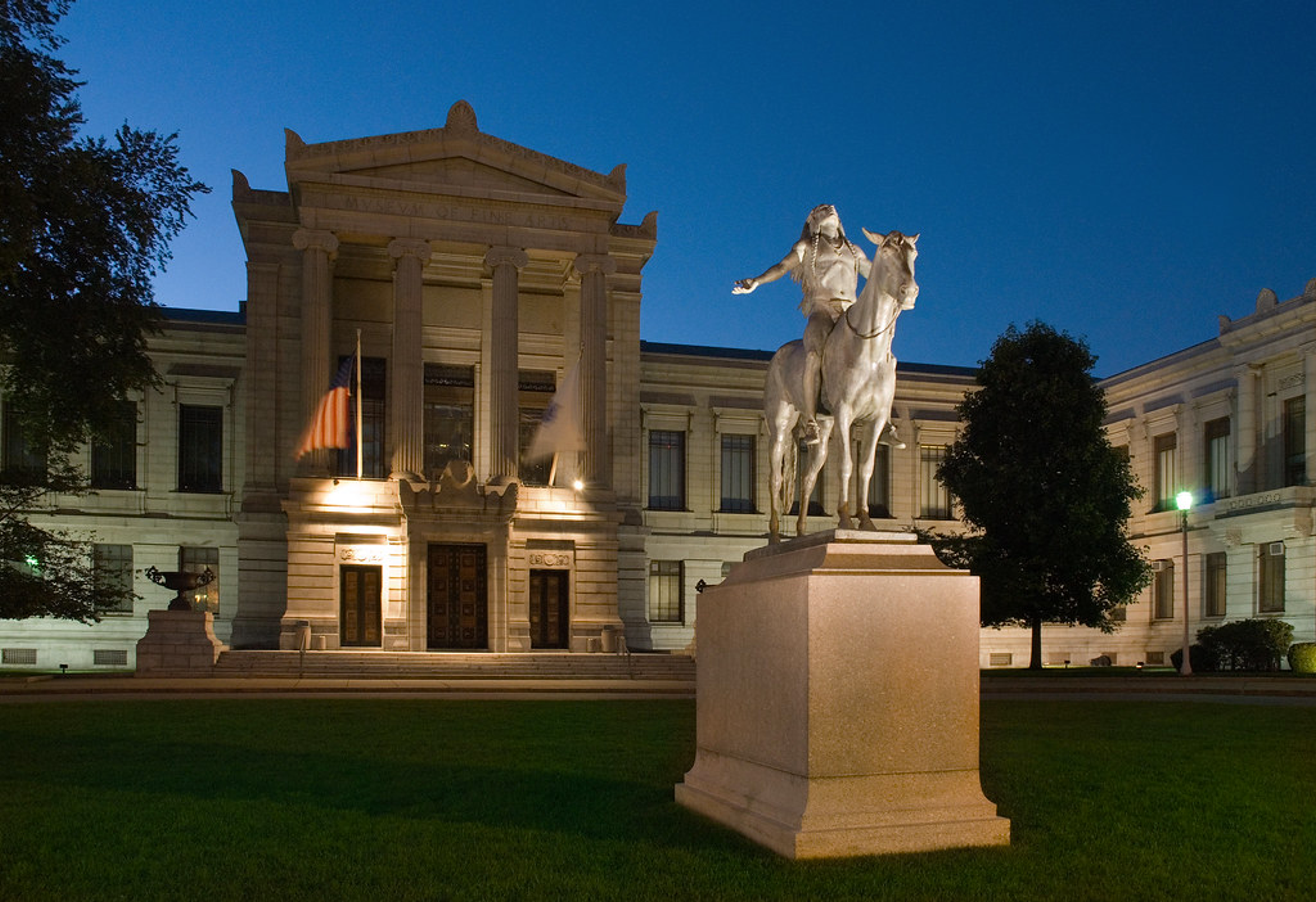 Image prise en extérieur du Museum of Fine Arts, Boston, le soir. Elle montre la façade du bâtiment ainsi qu'une statue équestre.