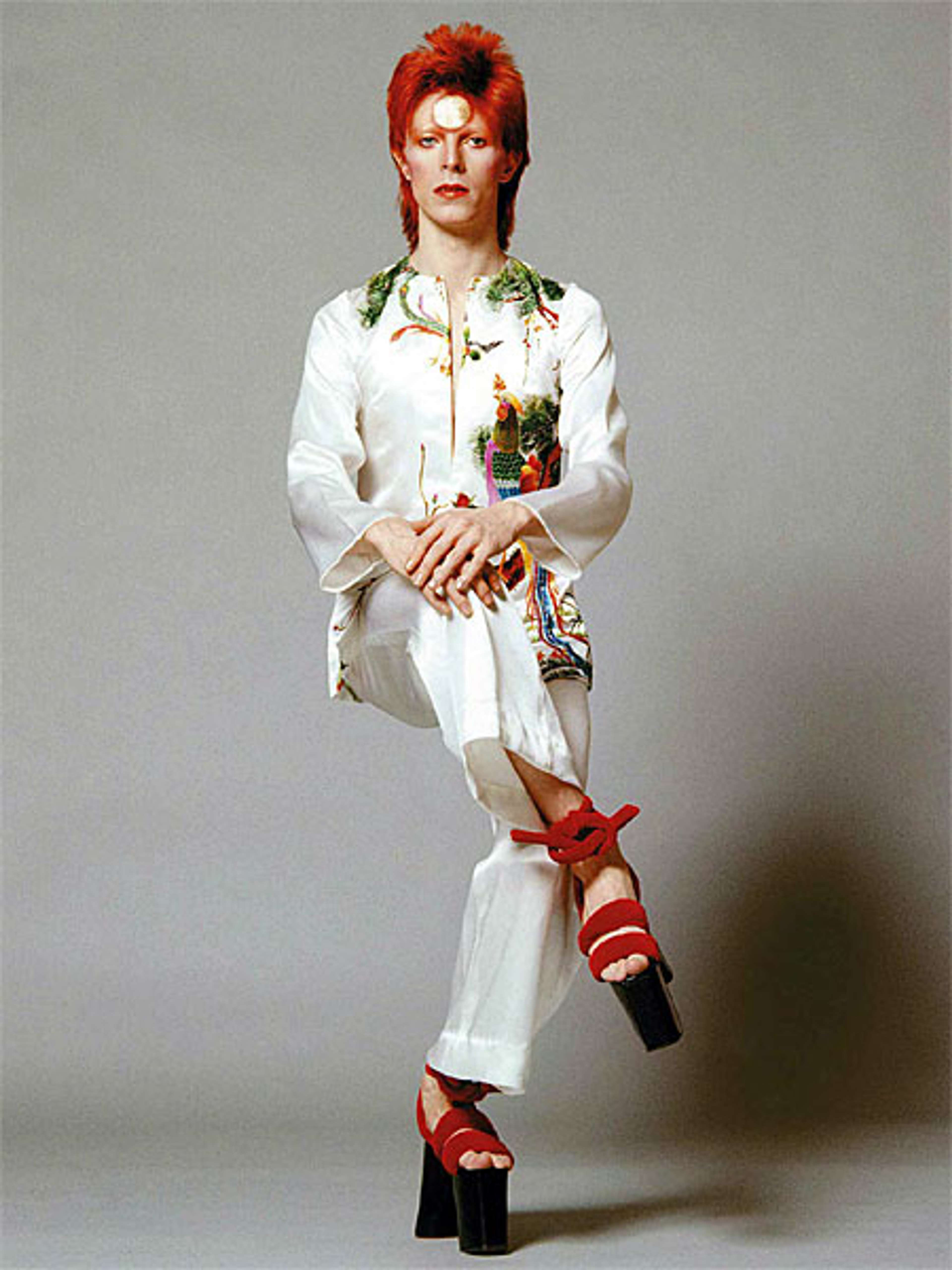 Photographie de David Bowie adoptant une pose assise dans le style mime.