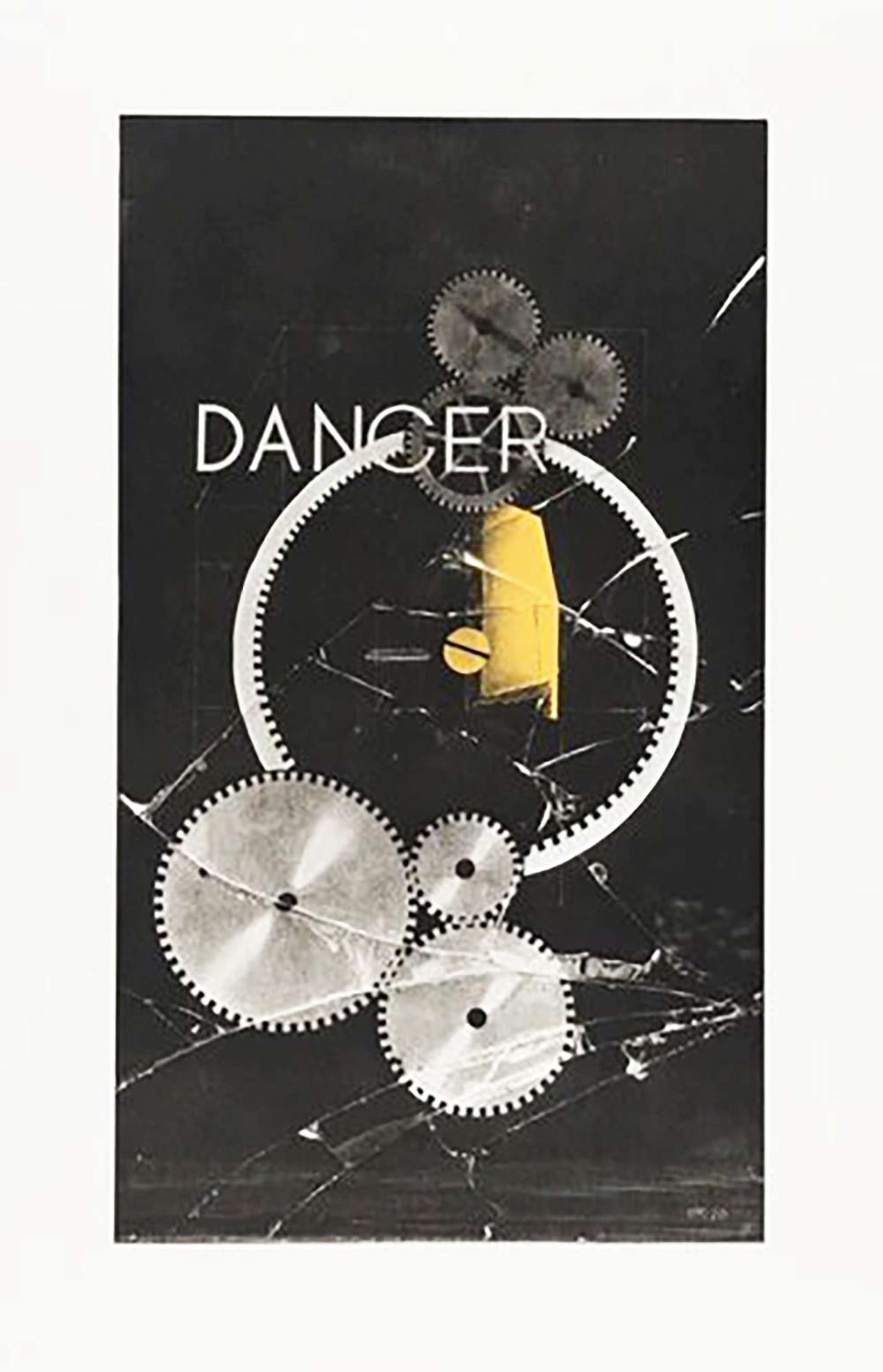 Photographie représentant plusieurs engrenages de tailles différentes, recouverts de verre fissuré. Le mot « DANCER » est inscrit en lettres capitales vers la moitié supérieure.