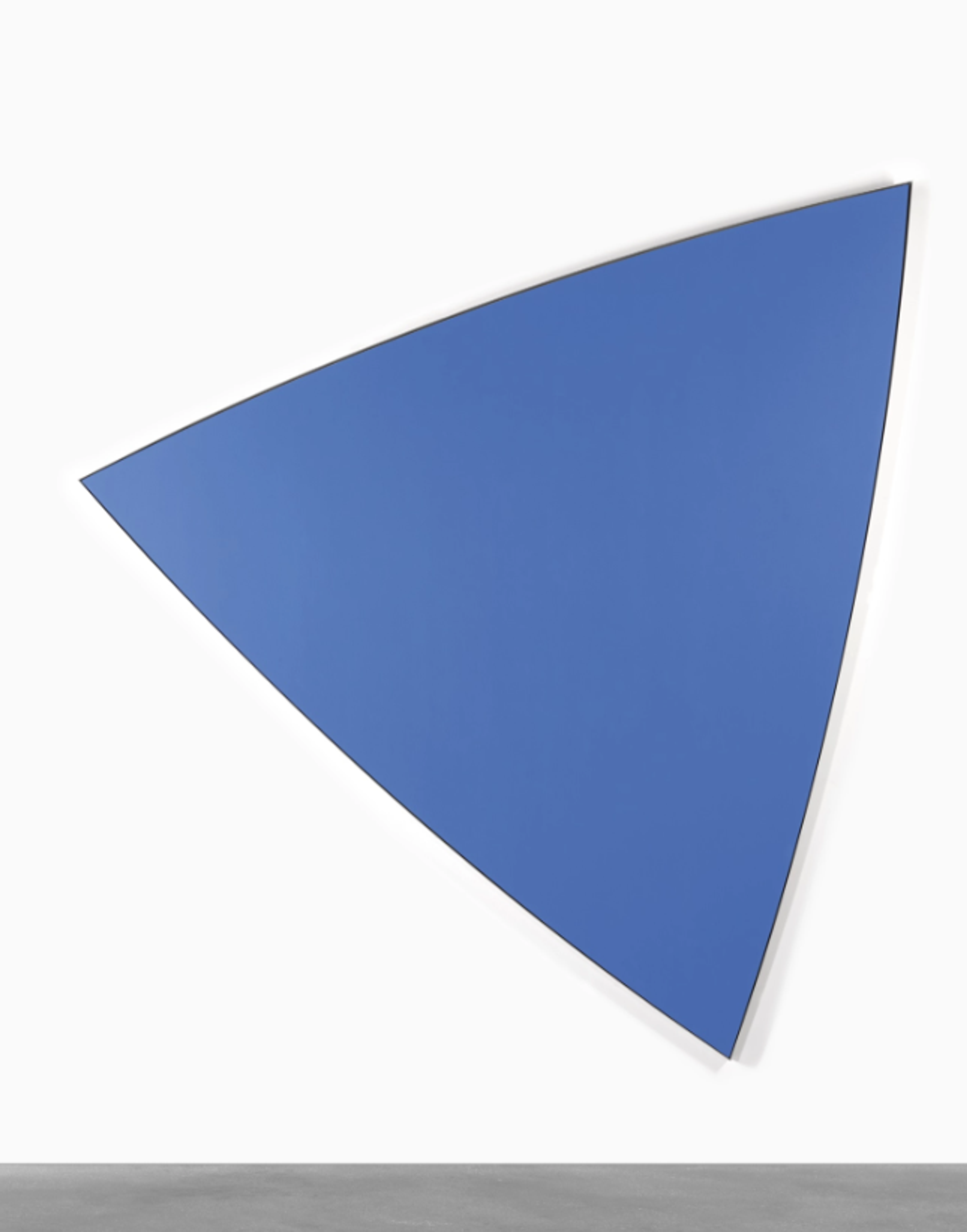 A blue triangular canvas panel, tilted so that the top of the triangle points to the viewer’s right. Each of the edges is the same length and has a gentle curve that makes the triangle slightly rounded. The shade of blue is deep primary and the finish is very even and smooth.