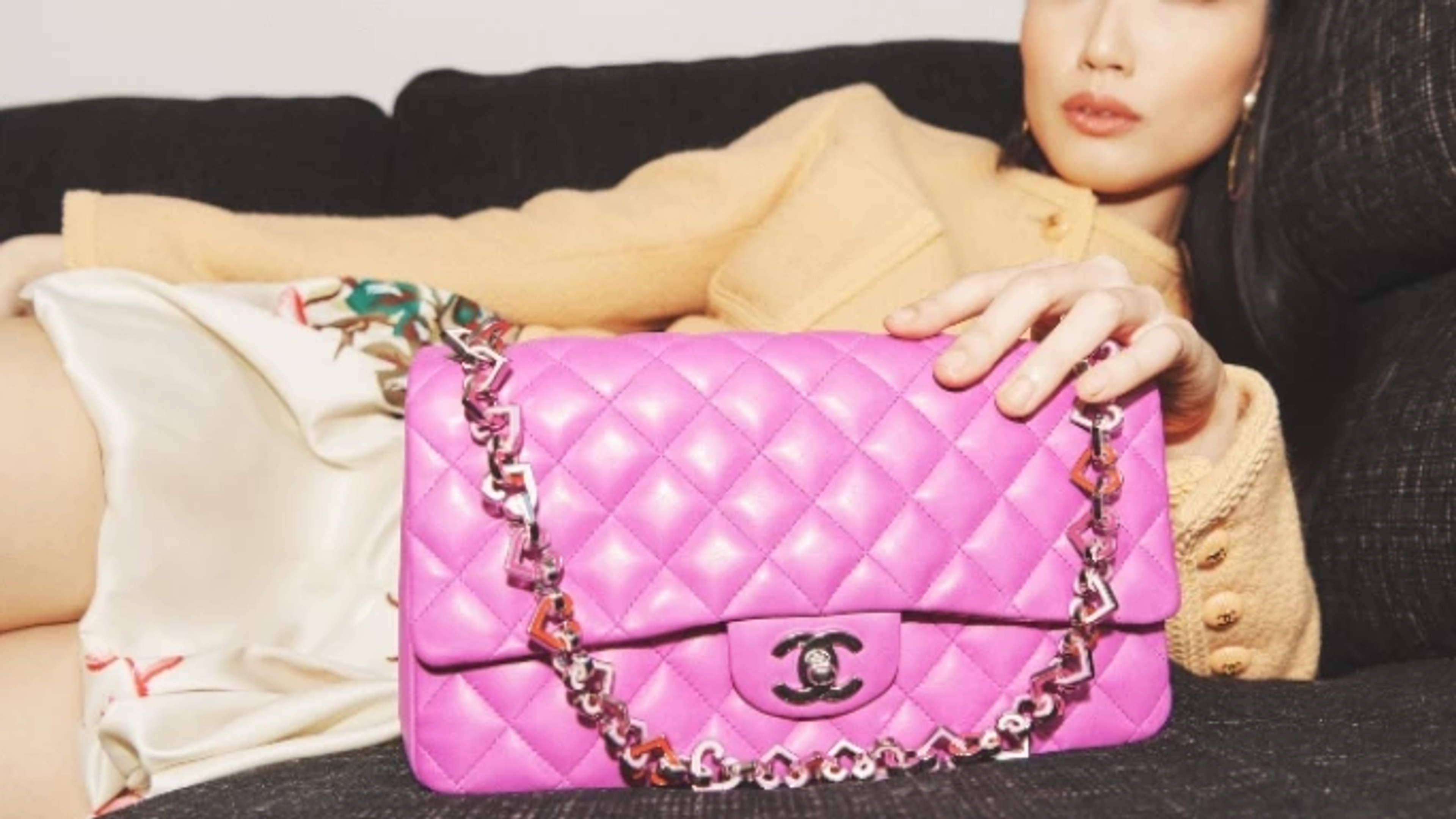 Une femme allongée portant un sac à main matelassé Chanel violet.