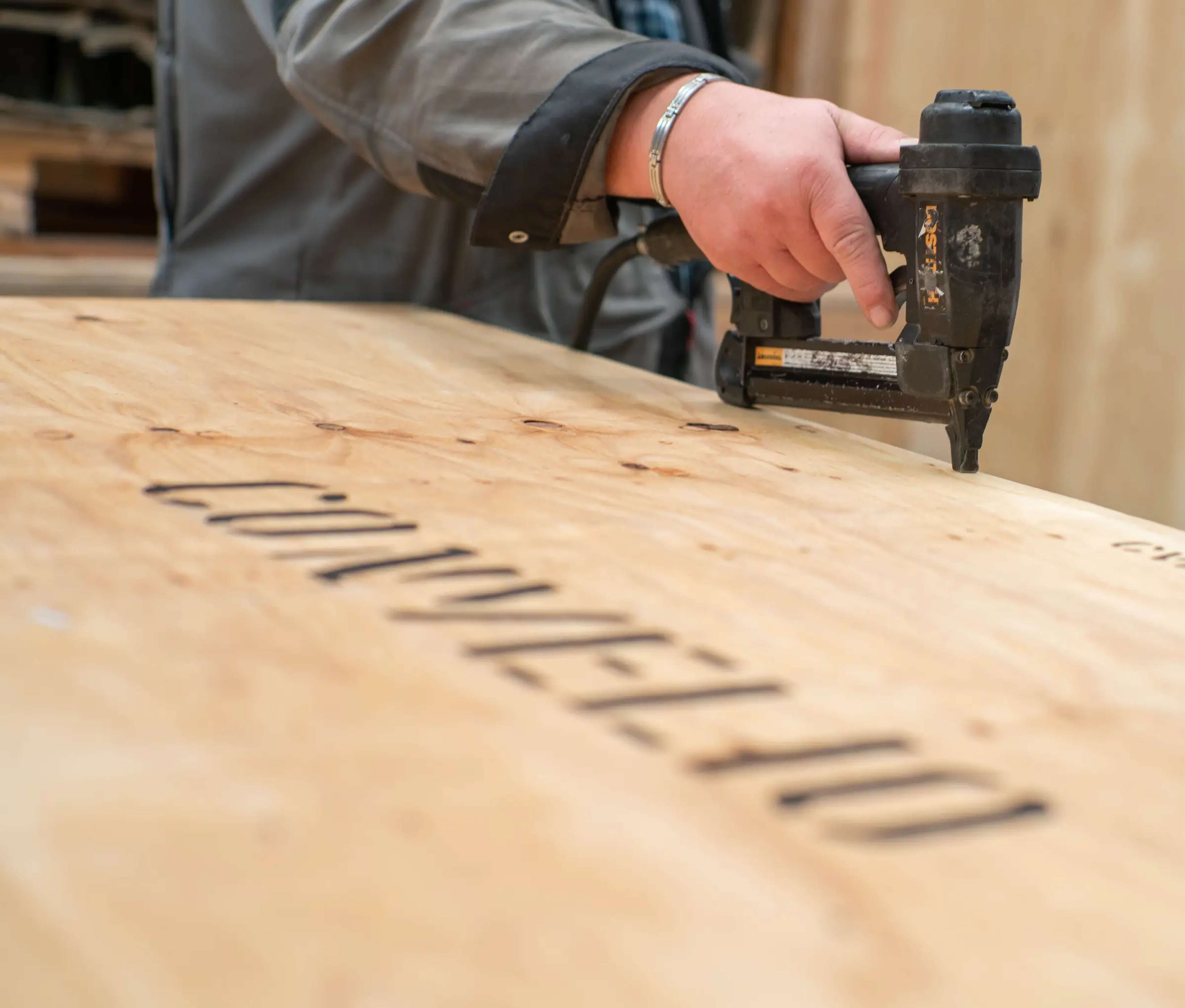 Une image d'une caisse d'expédition portant le nom de l'entreprise « CONVELIO » estampillé en noir, une main tenant une perceuse contre la caisse en bois.