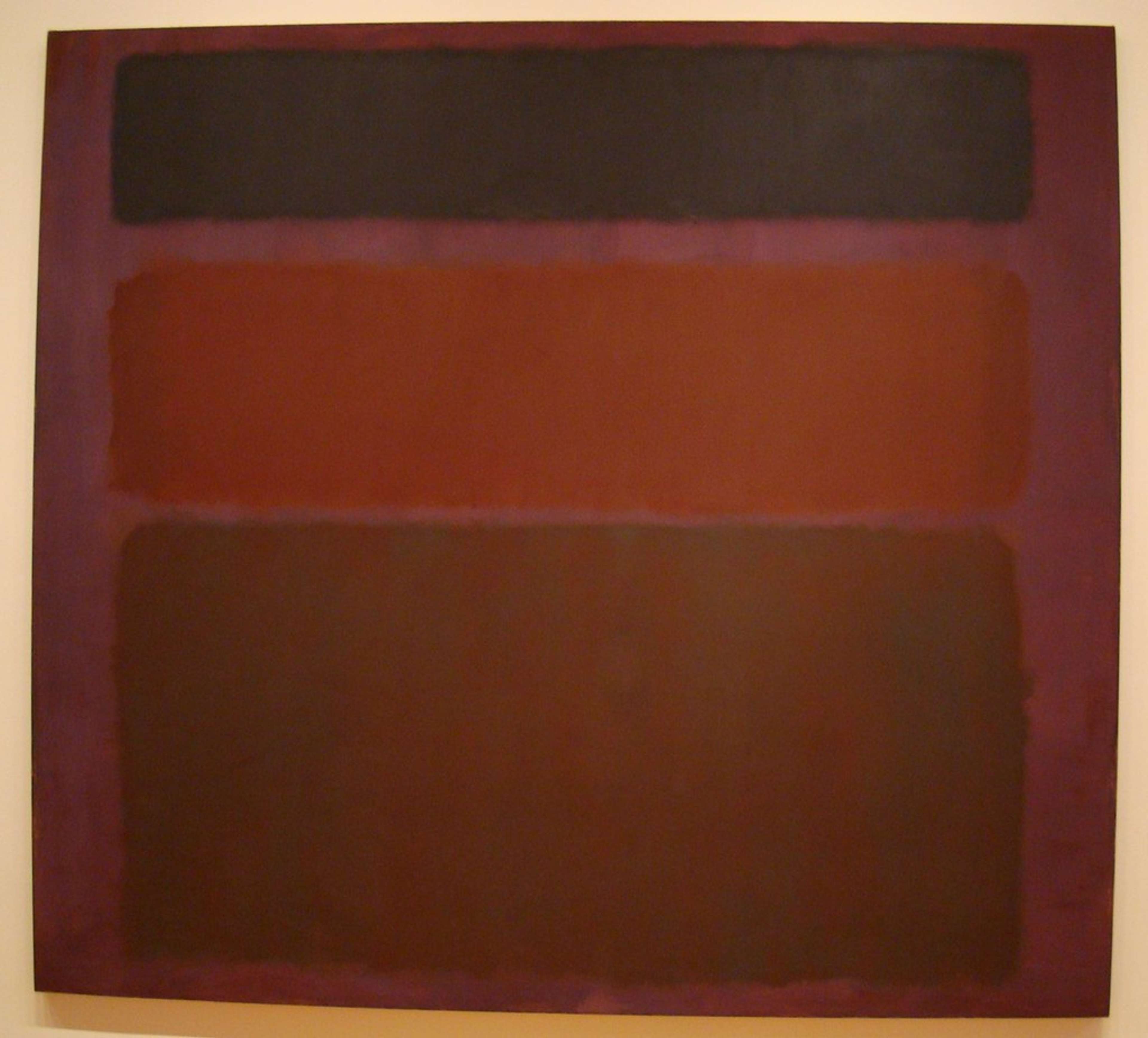 Une peinture abstraite intitulée « No. 16 (Red, Brown, and Black) » représentant trois blocs de couleur – rouge, brun et noir – se fondant les uns dans les autres sur une grande toile rectangulaire.