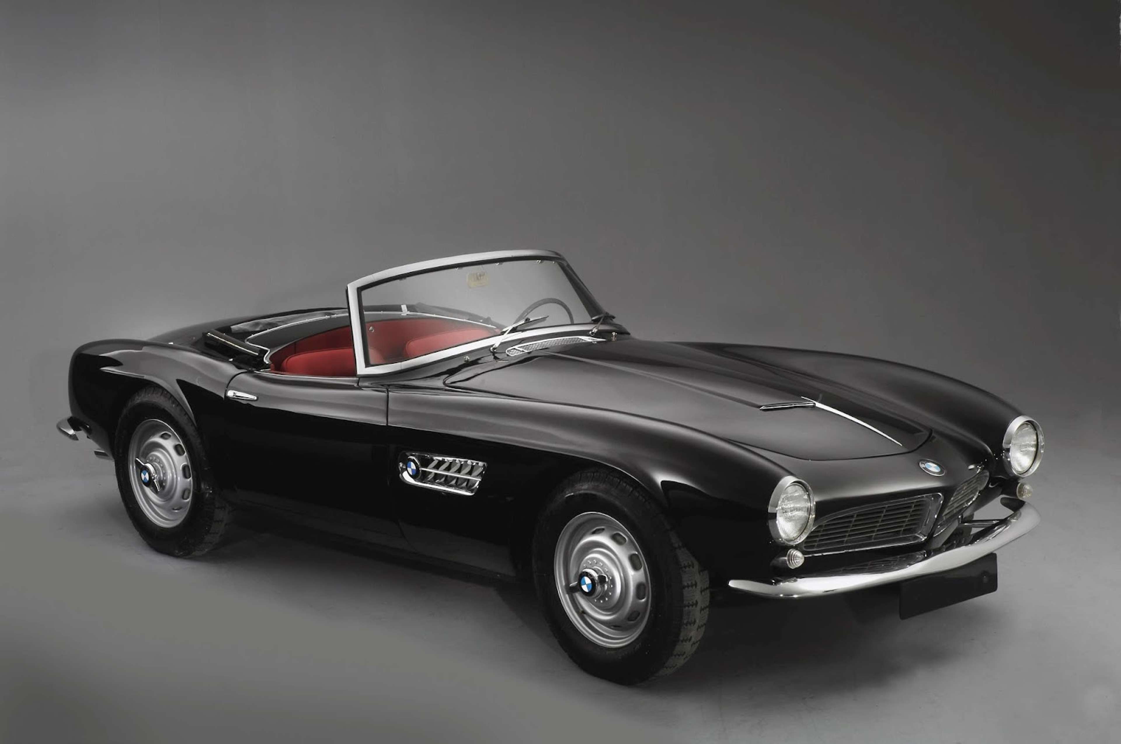 Une BMW 507 noire de 1957 sur un fond de studio sombre.