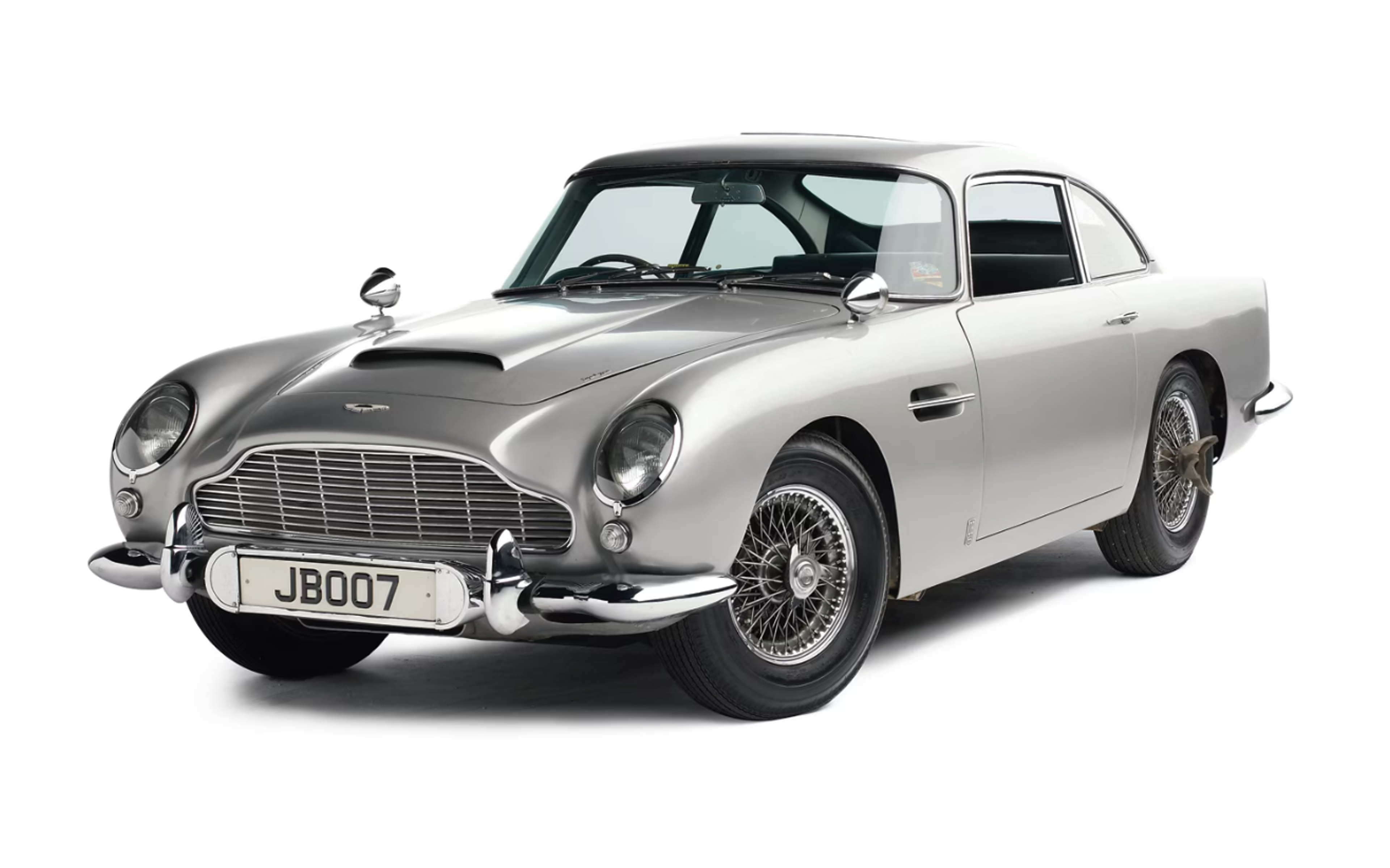 Une Aston Martin DB5 de 1965 de couleur argentée sur fond blanc, apparue dans le film de James Bond.