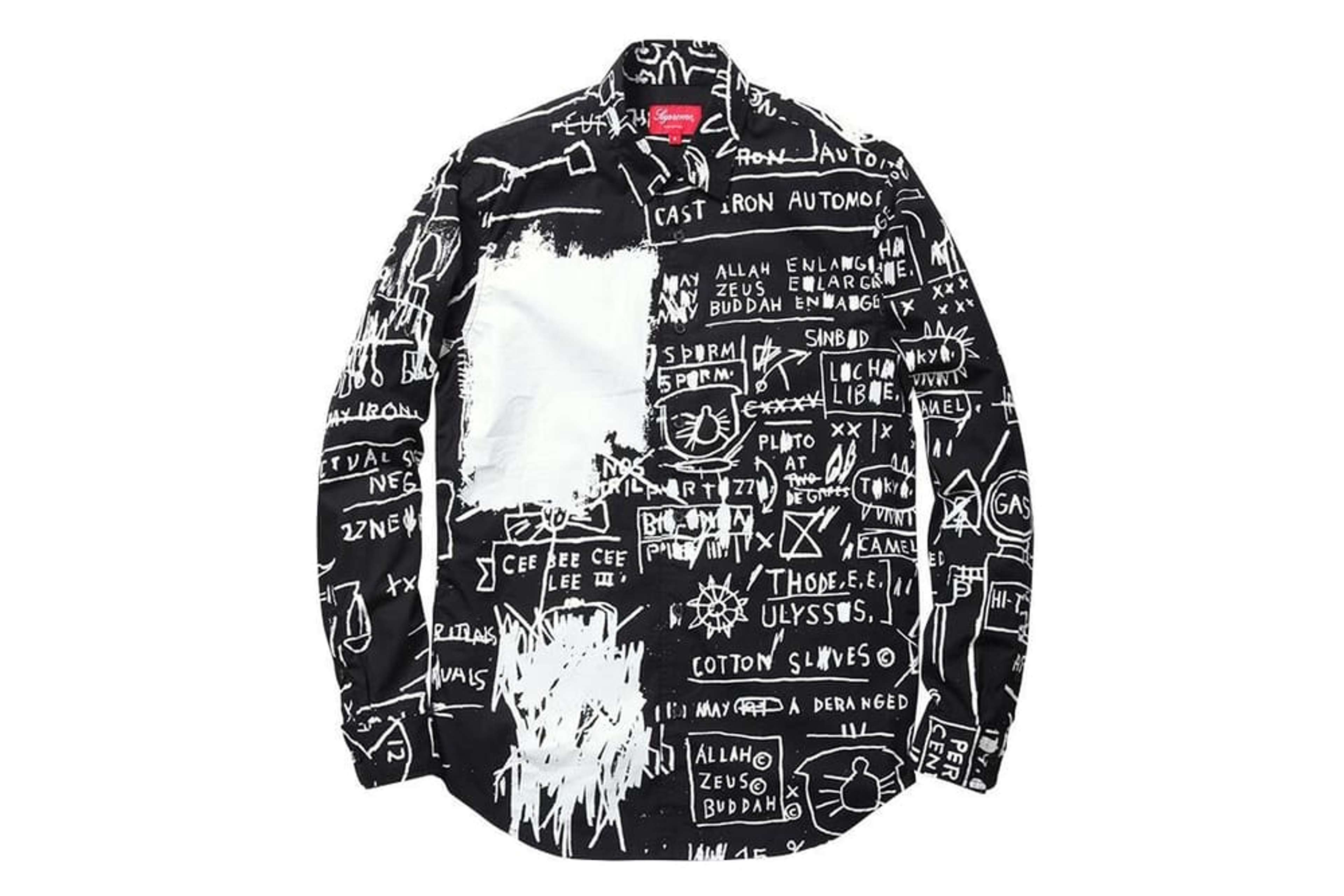 Une image d'un t-shirt noir orné de symboles et de gribouillis blancs de Basquiat, par la marque Supreme.