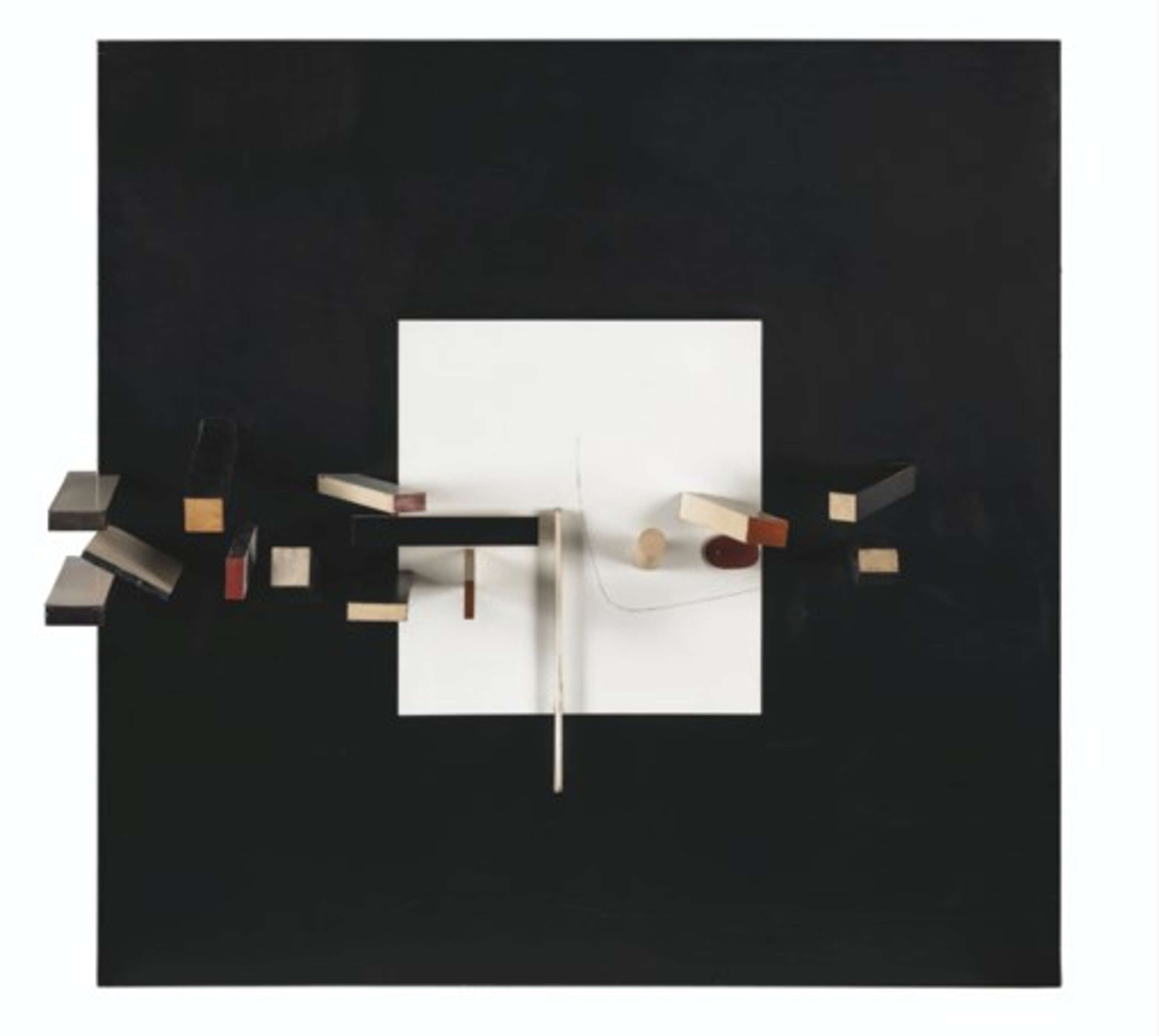 A black square canvas features a smaller white square positioned centrally. Starting from the left-hand edge, three-dimensional objects made of various materials intertwine and intersect, extending almost to the opposite side of the canvas.