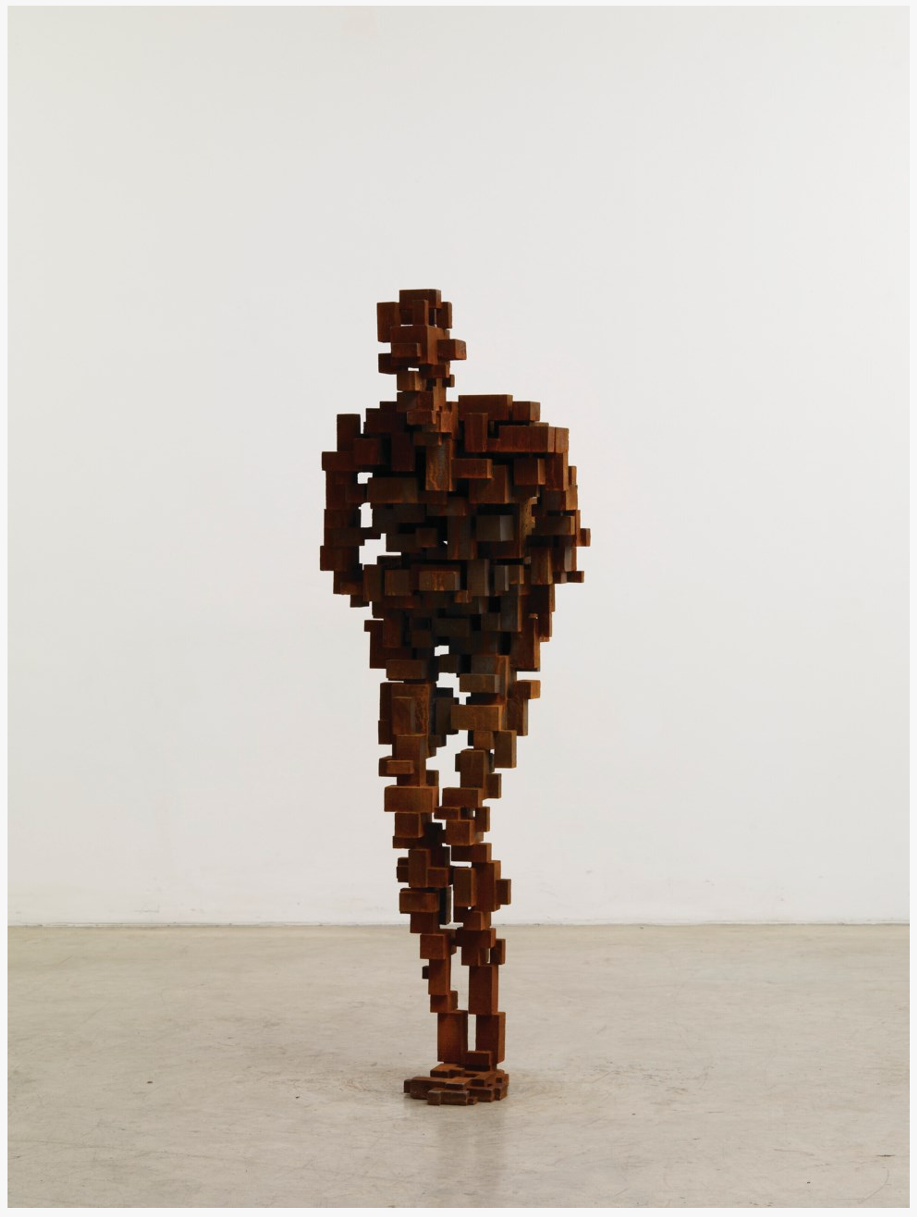 Une sculpture en fonte de 160 centimètres, composée de divers petits blocs, représentant une silhouette humaine debout, recroquevillée.
