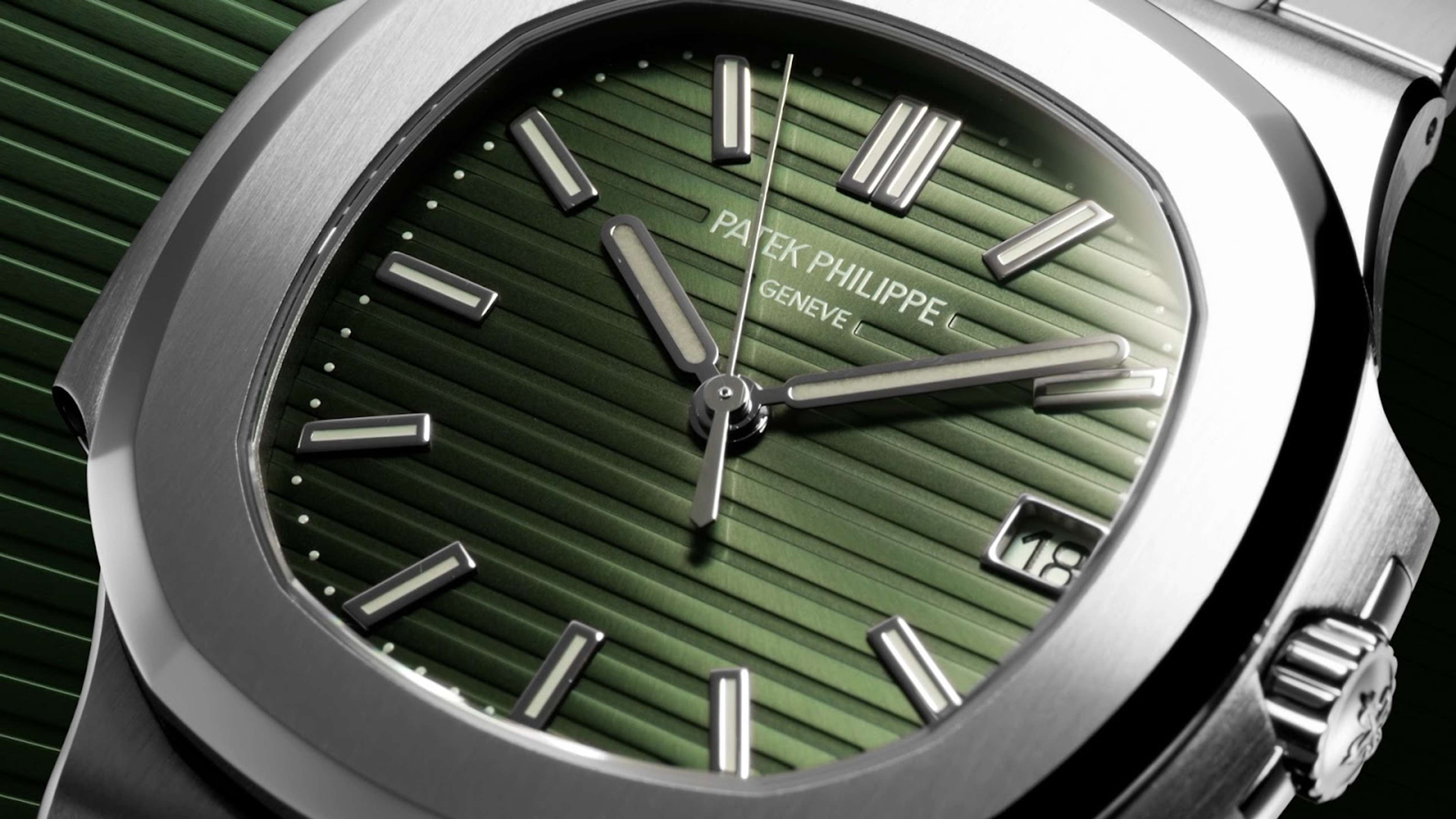 Une Patek Philippe Nautilus, lancée pour la première fois en 1976. L'image est un gros plan du cadran de la montre, qui est vert et serti dans un boîtier en métal argenté.