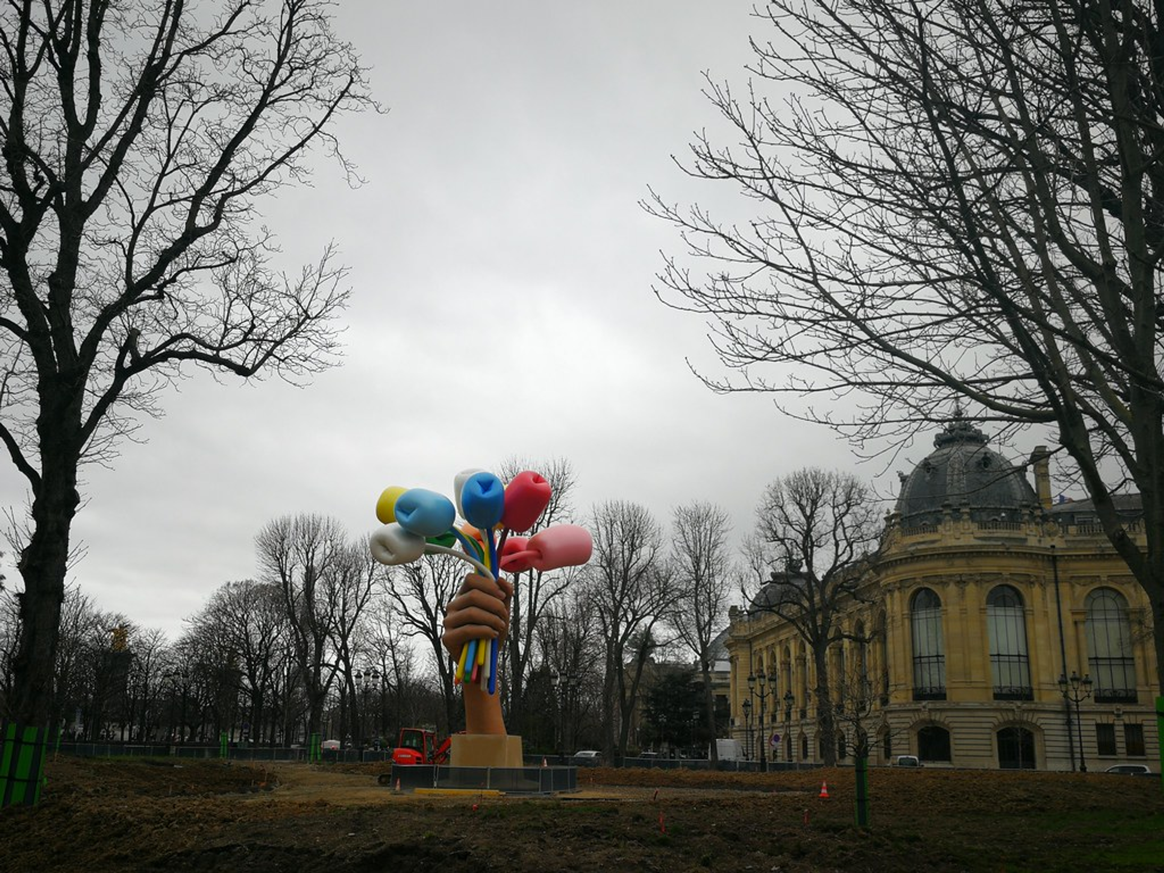 Dans cette sculpture de Jeff Koons, une main monumentale tenant plusieurs ballons en forme de fleurs émerge de la terre.