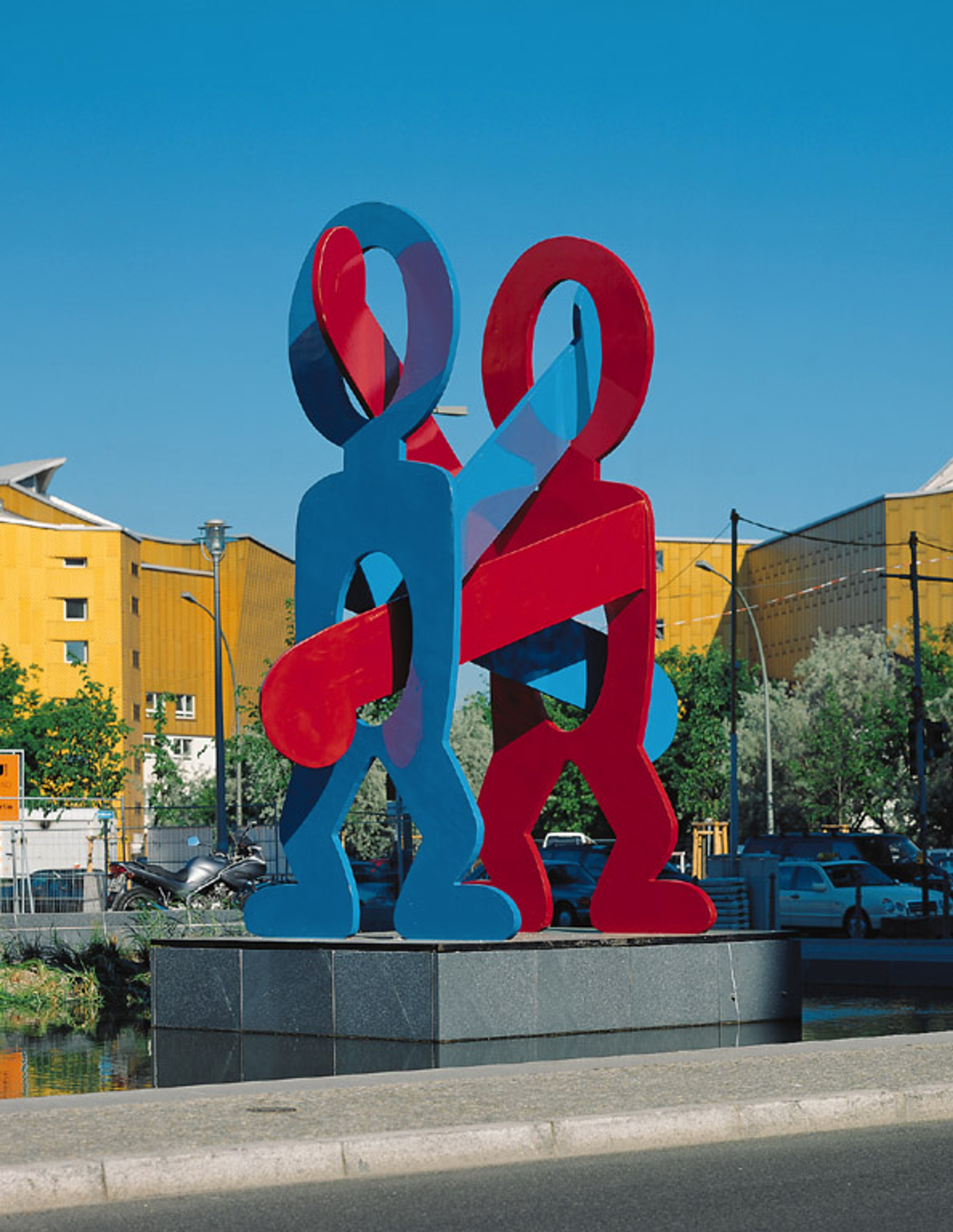 « Untitled (Boxers) » de Keith Haring. Vue d'installation d'une sculpture en acier peinte en rouge et bleu sur une plateforme grise surélevée.