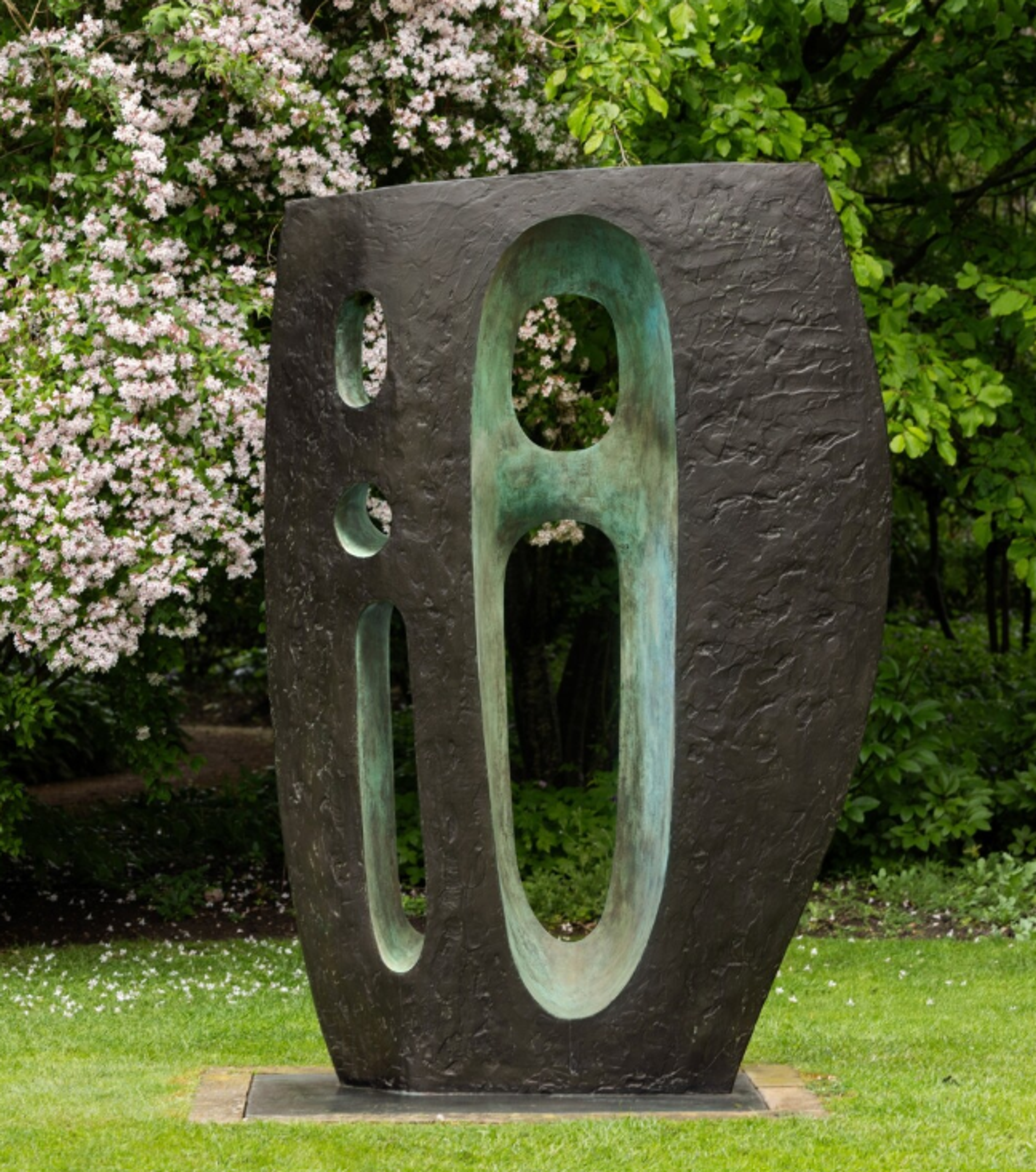 An oval-shaped bronze sculpture with a smooth, rounded exterior and a hollowed turquoise-green interior space, with cut-through circular and oblong windows. The form resembles a seed pod or organic vessel, with the exterior surface having a metallic grey patina while the interior cavity provides a striking colour contrast.