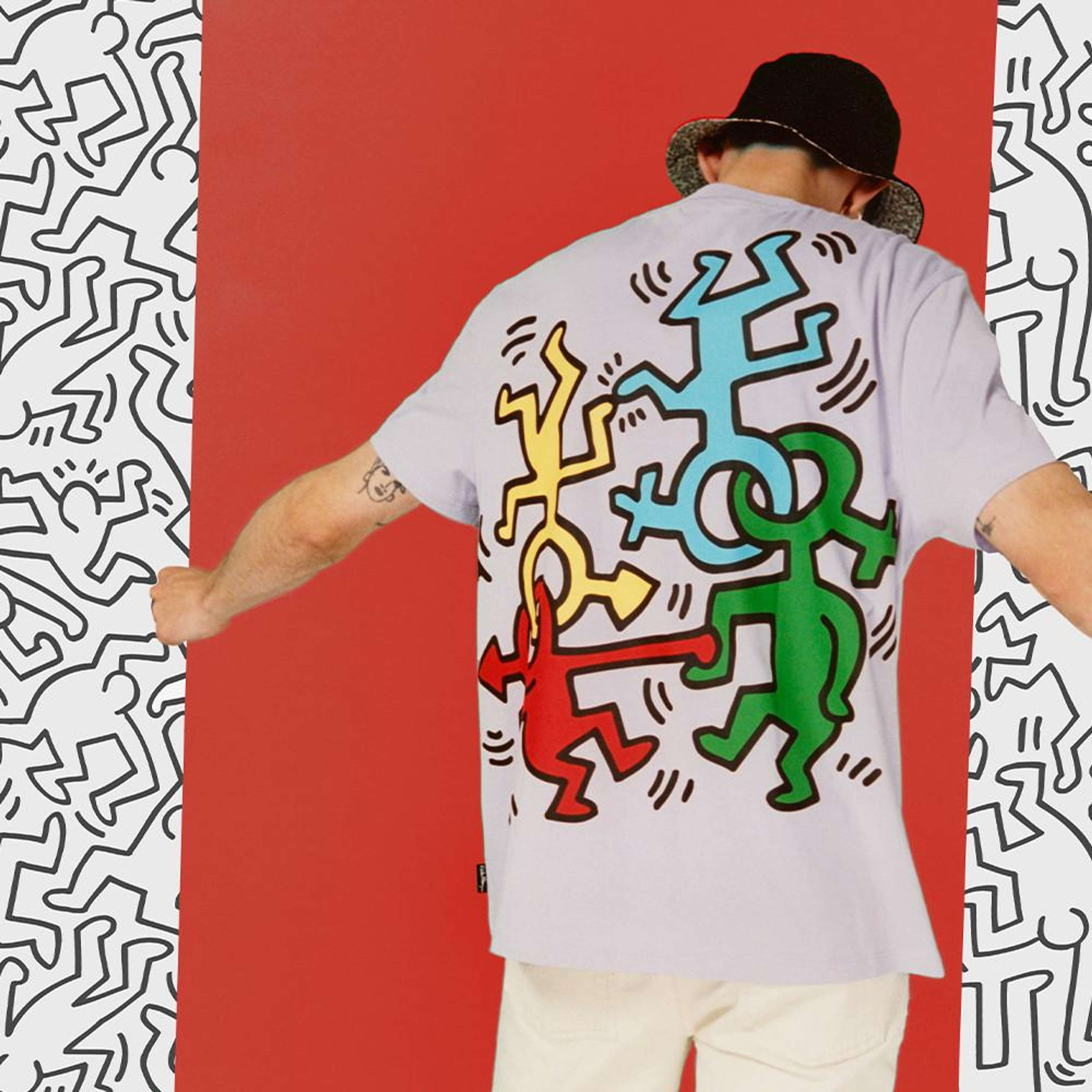 Une image d'un mannequin portant un t-shirt Primark orné de quelques motifs de Keith Haring, se tenant devant un arrière-plan richement décoré des silhouettes signature de l'artiste.