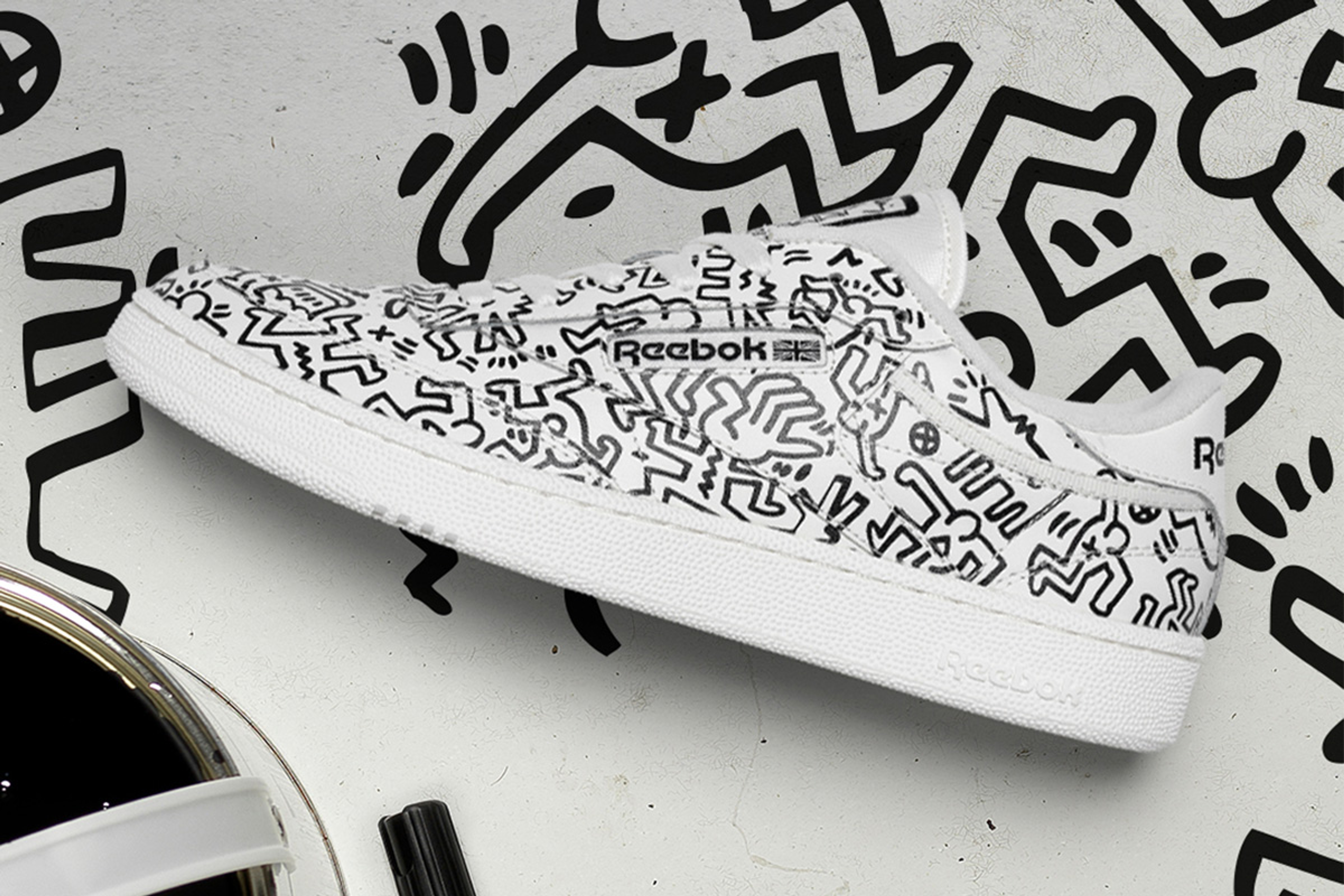 Une image d'une basket blanche Reebok, entièrement décorée des "Dancing Figures" de Keith Haring.