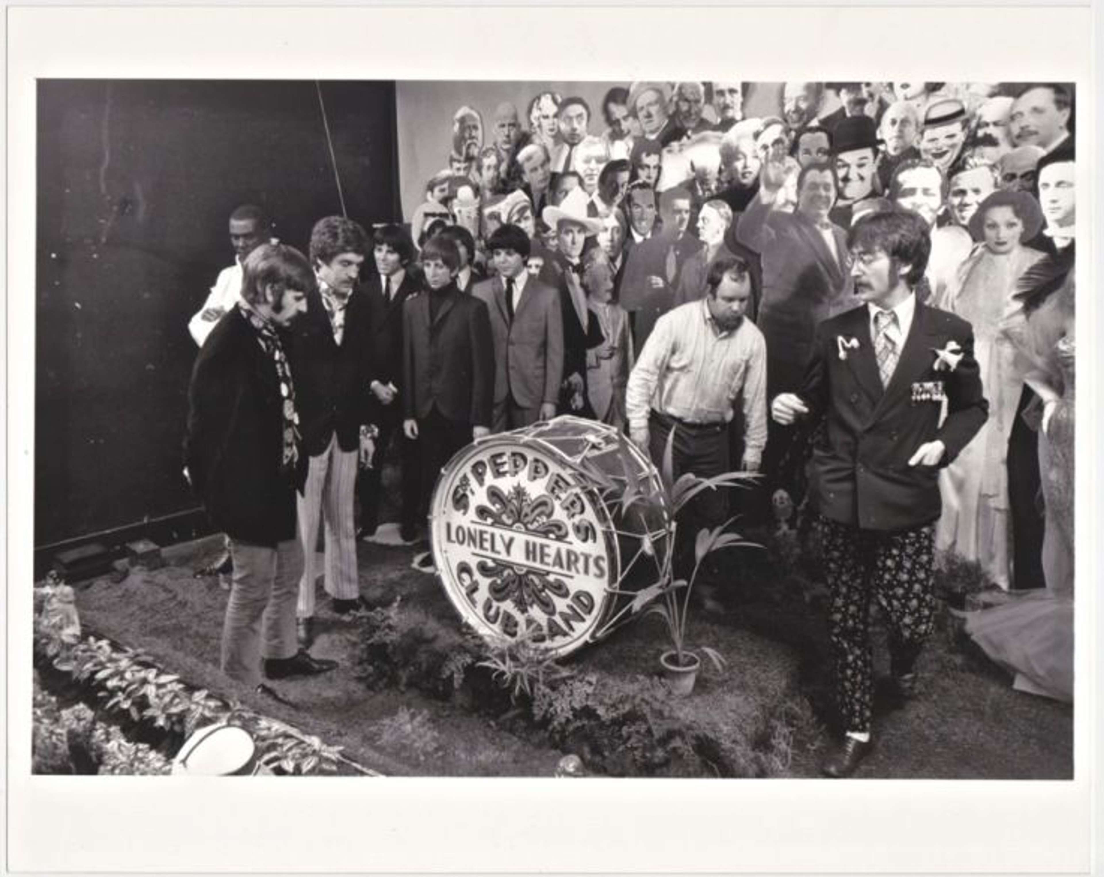 Photographie en noir et blanc du groupe The Beatles et de l'artiste Peter Blake lors de la séance photo pour la pochette de leur album Sgt. Pepper’s Lonely Hearts Club Band.