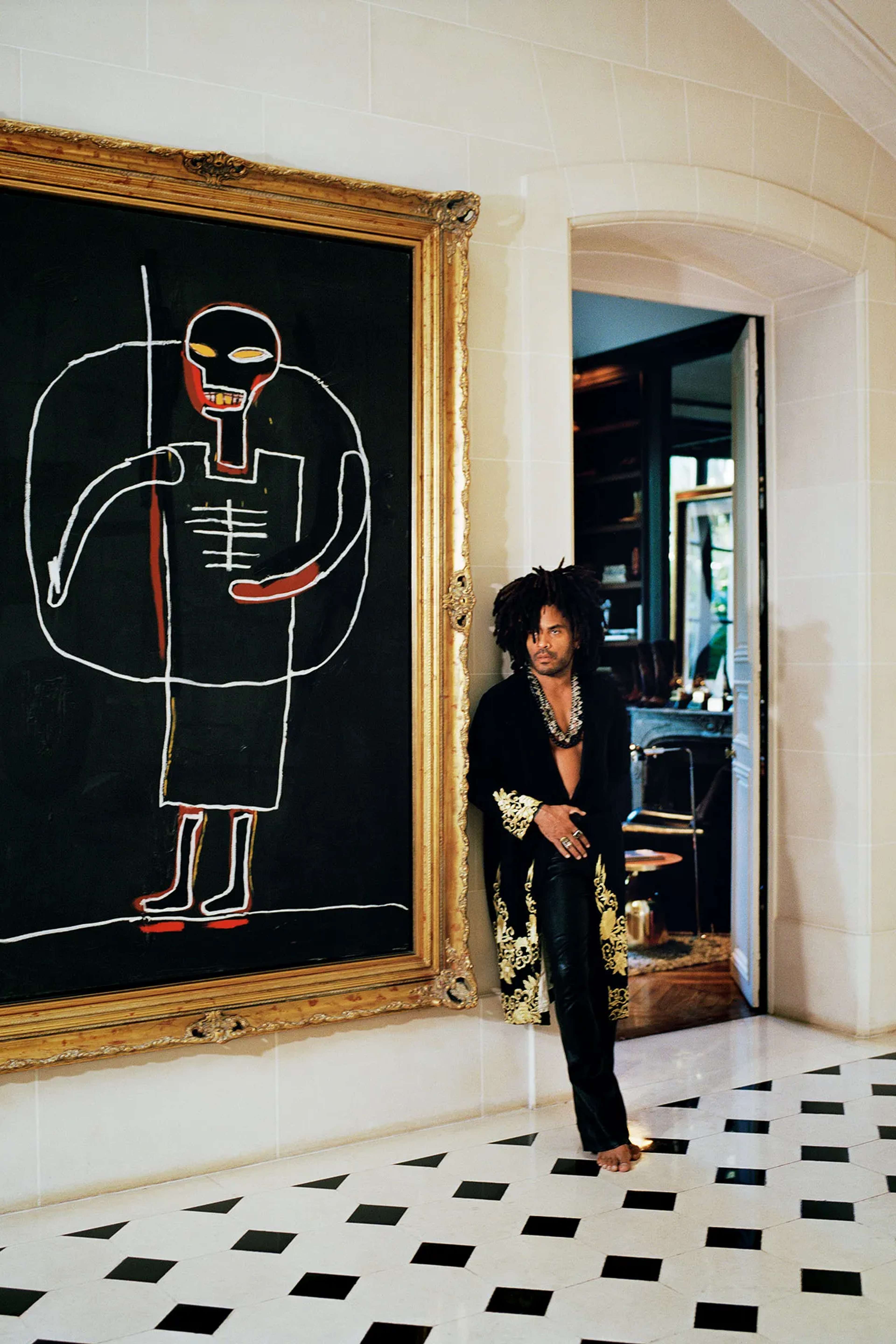 Lenny Kravitz debout à côté d'un tableau de Jean-Michel Basquiat dans sa maison.