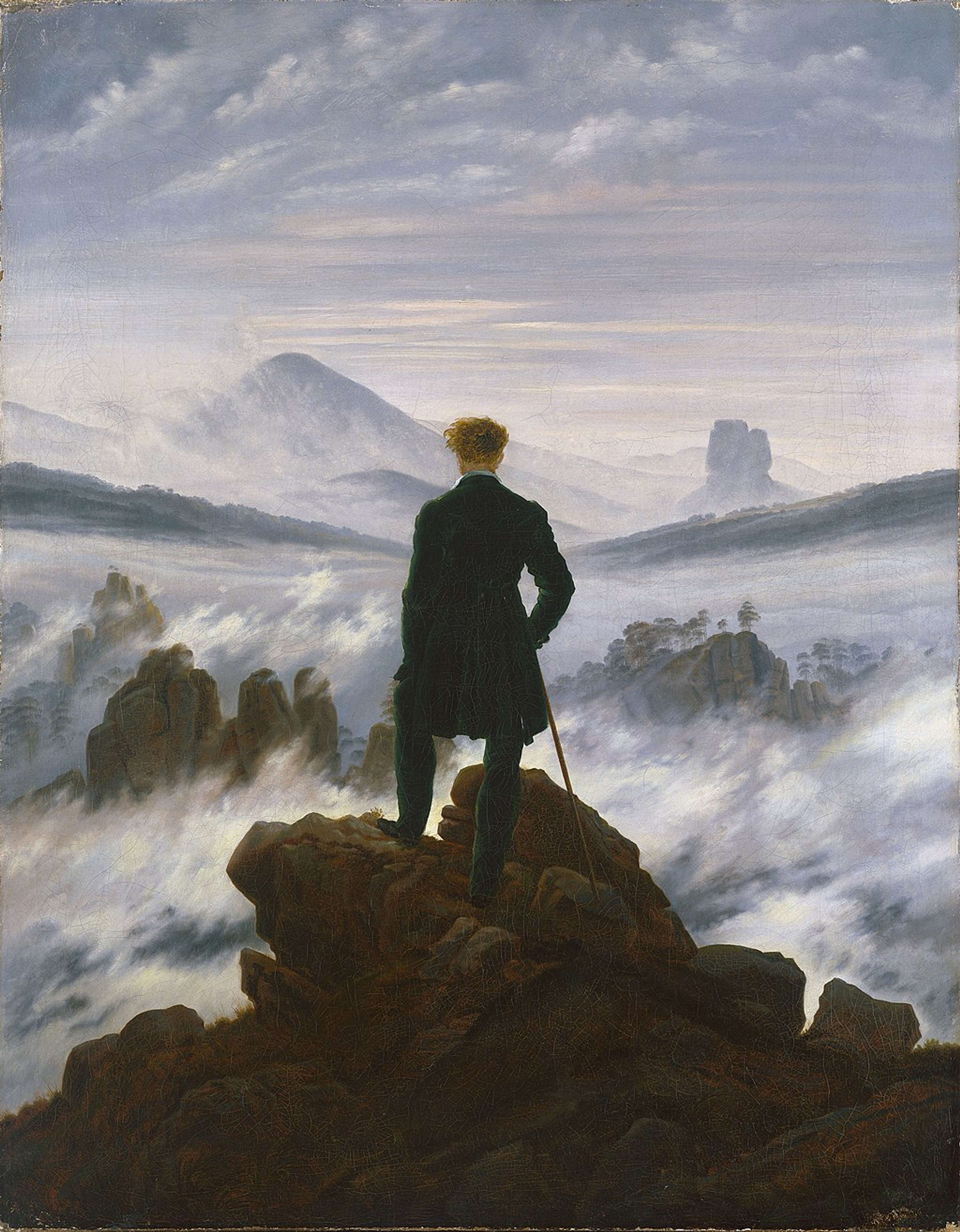 Un homme seul, vêtu d'un manteau sombre, se tient au sommet d'un pic rocheux, contemplant un vaste paysage de montagnes perçant une mer de brouillard tourbillonnant sous un ciel pâle et nuageux.