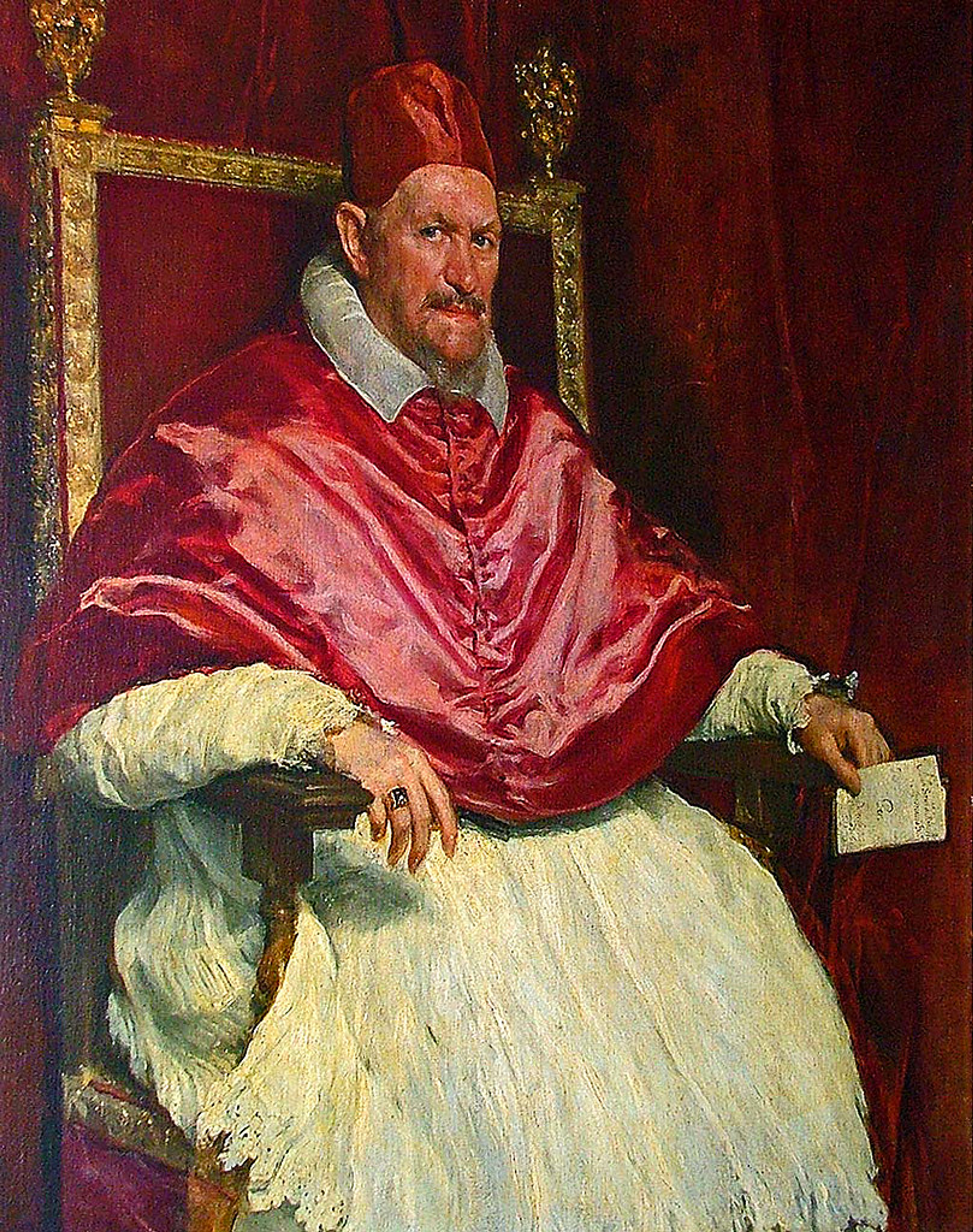 Portrait d'Innocent X par Diego Velasquez. Un pape assis, vêtu de l'habit papal, tenant un parchemin à la main.