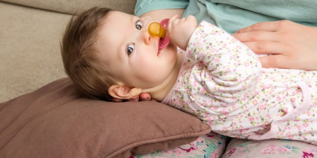 Calm baby being comforted by a parent during teething, illustrating gentle and supportive care for teething discomfort.