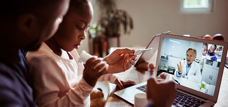 Parent and child attending an online homeopathy consultation with a certified homeopathic doctor via video call from home.