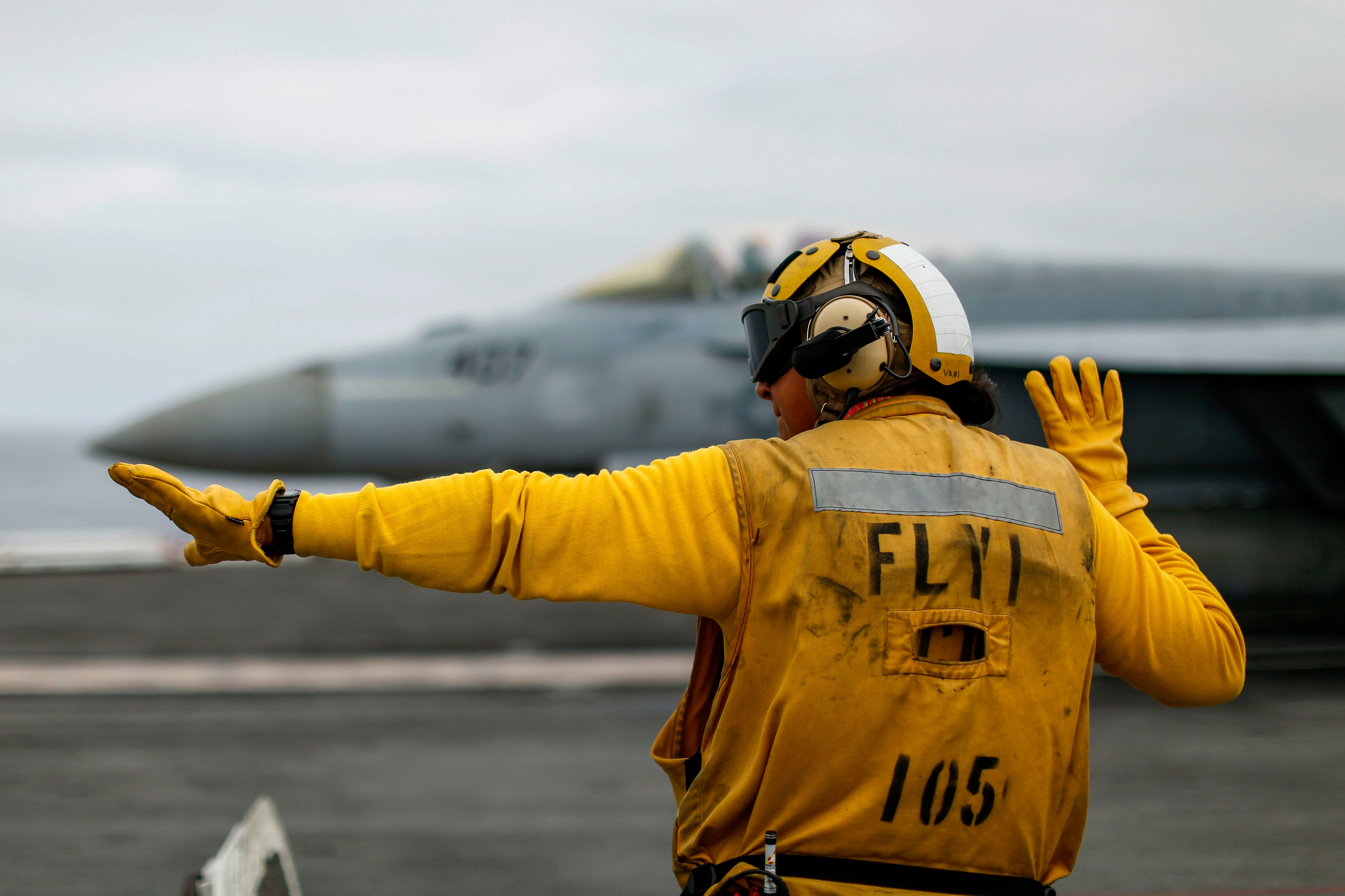 Navy Petty Officer 2nd Class Estrella Santoya signals to an F/A-18E Super Hornet on the flight deck of the USS Abraham Lincoln in the Pacific Ocean, Nov. 6, 2021.