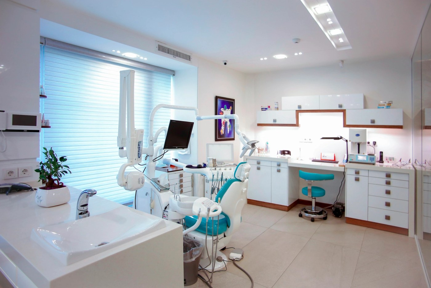 A modern dental treatment room with a chair and overhead equipment